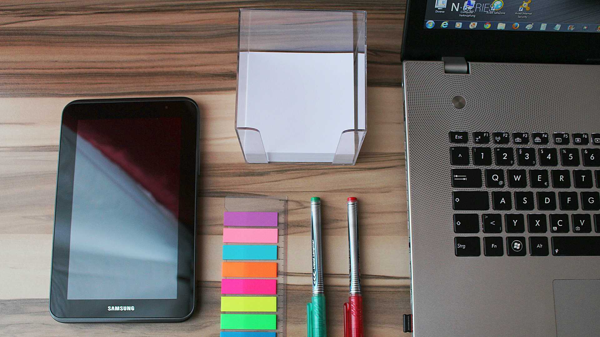 desk with laptop, sticky notes, tablet