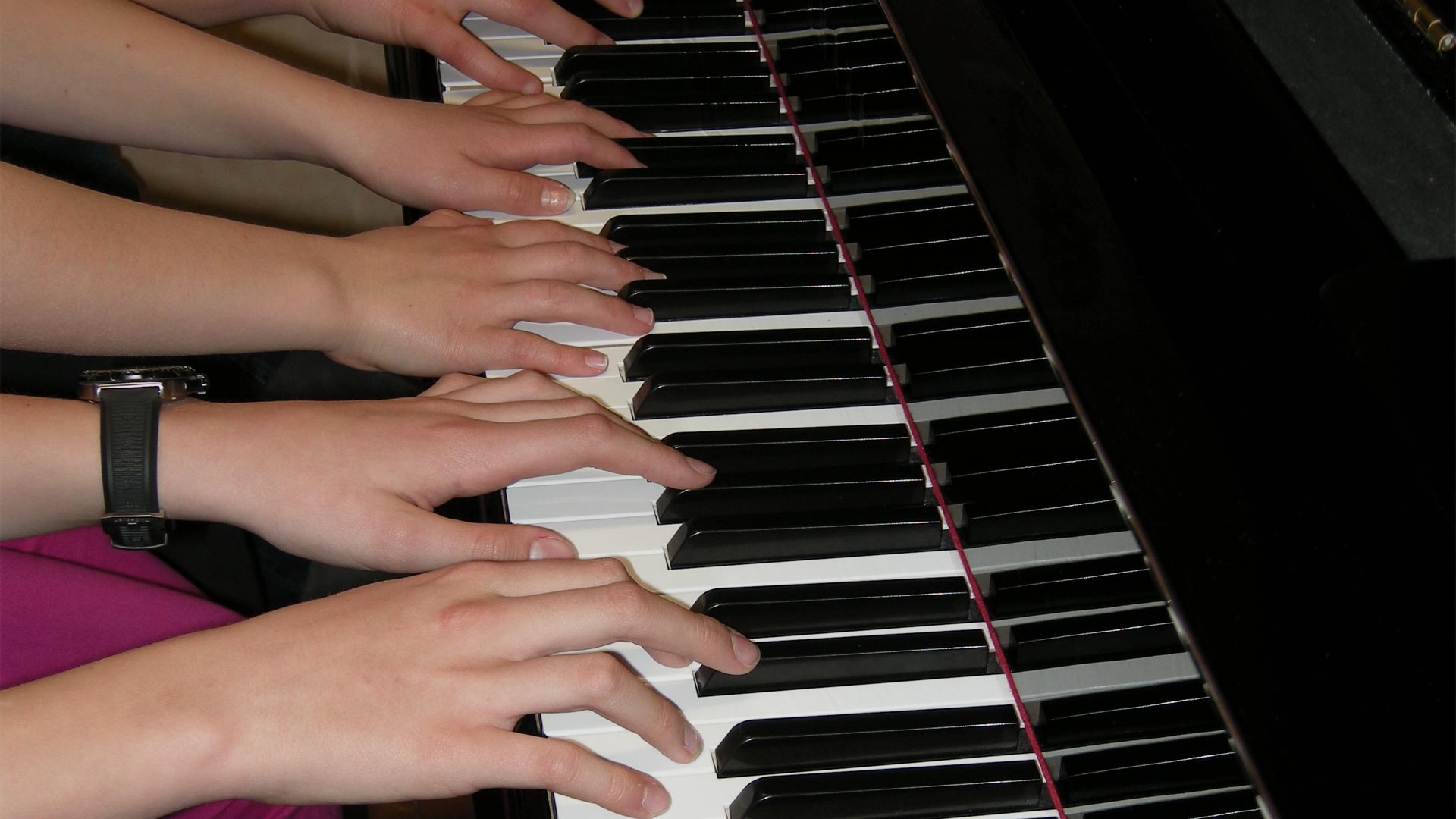 Three people playing piano