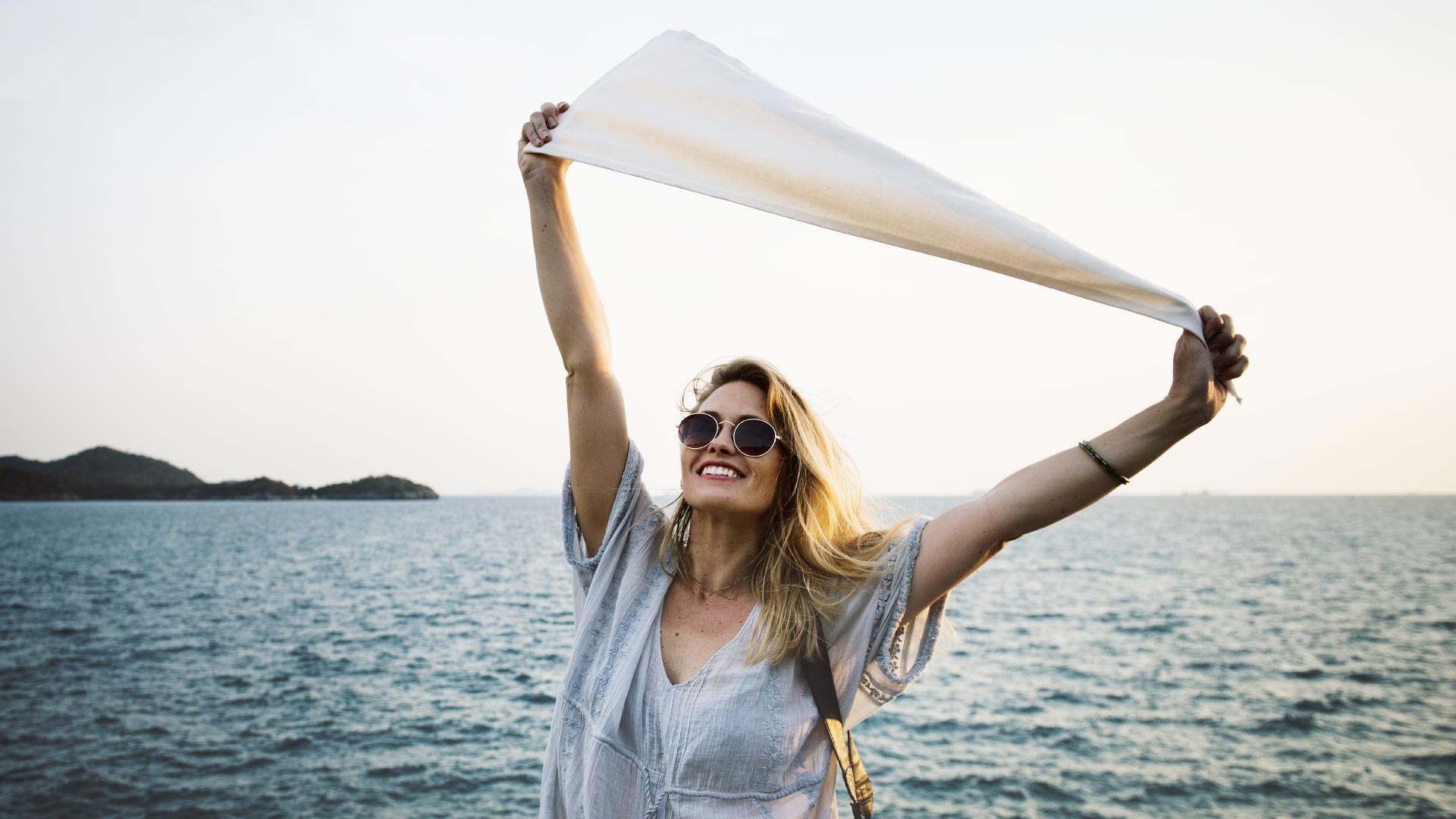 Girl holding white flag next to water