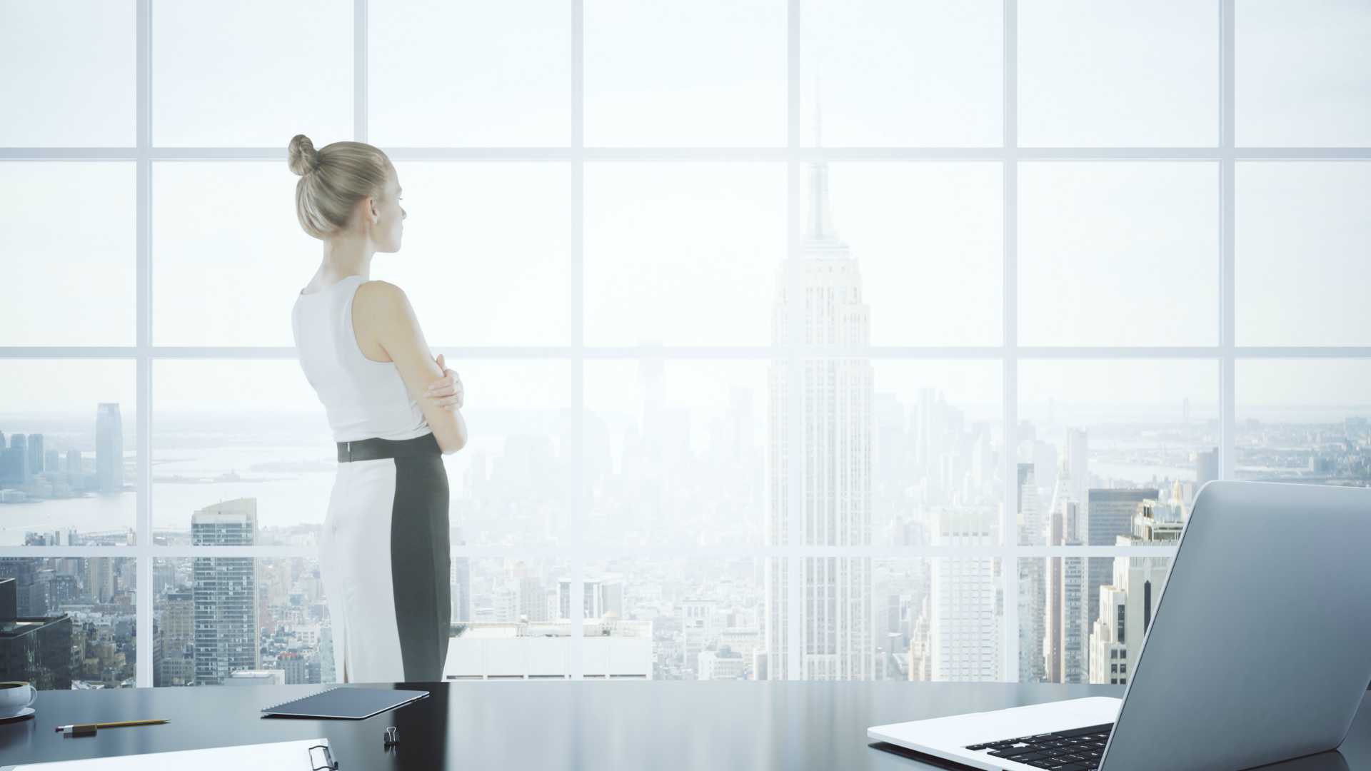Businesswoman standing in a large office at the top of a skyscraper