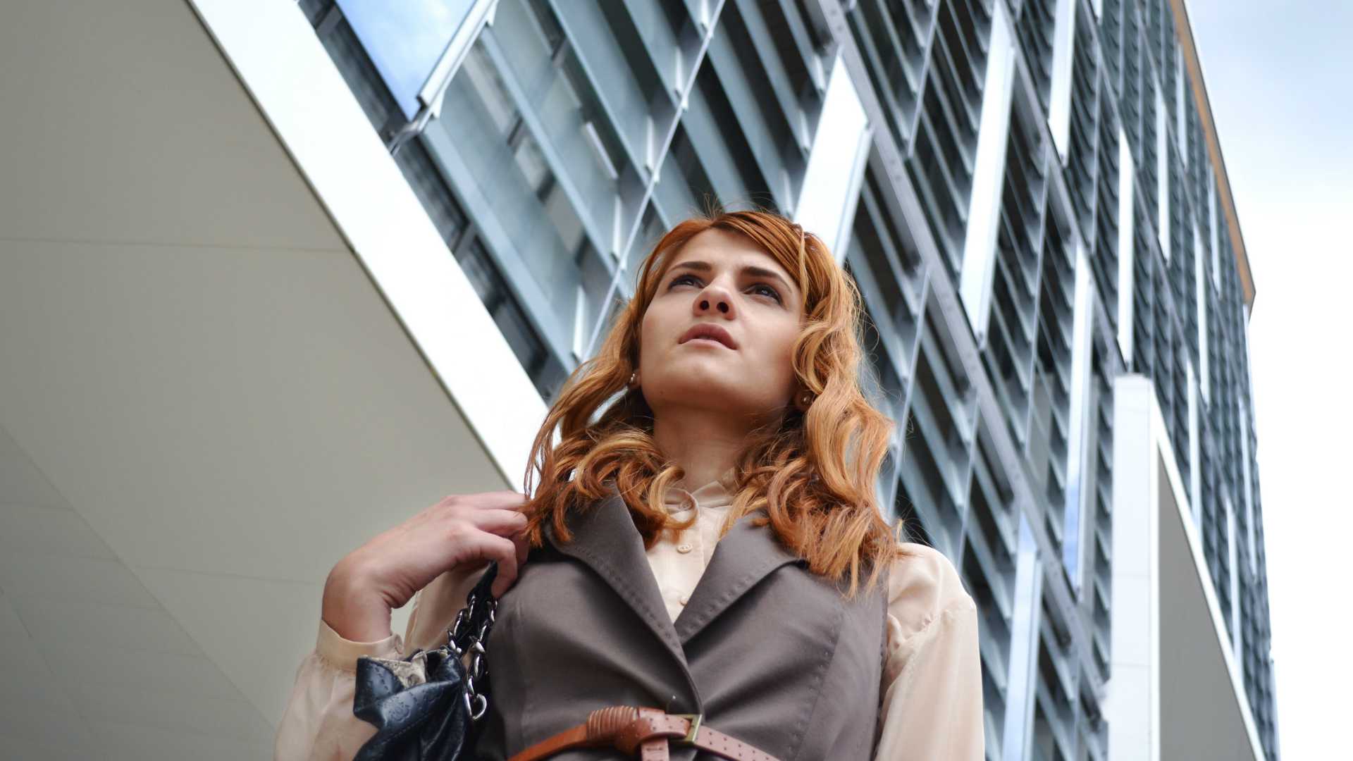 young woman walking in front of a skyscraper