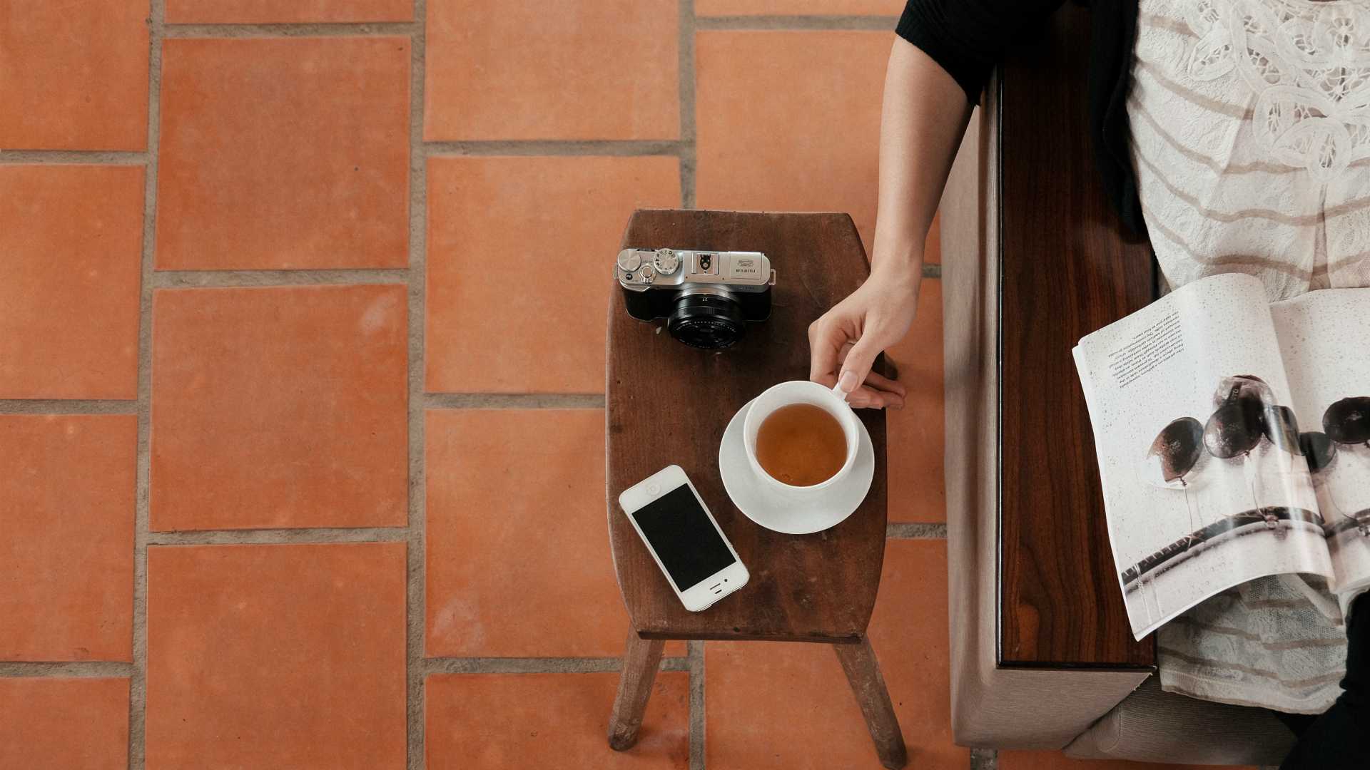 person reading a magazine and drinking tea
