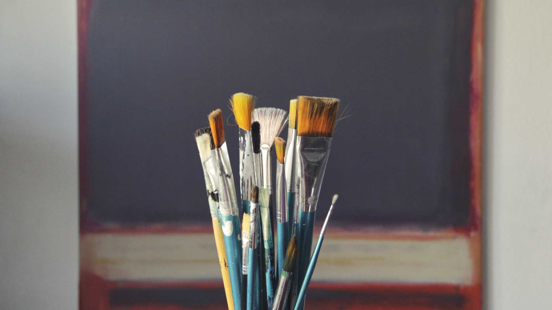 paintbrushes in front of a canvas