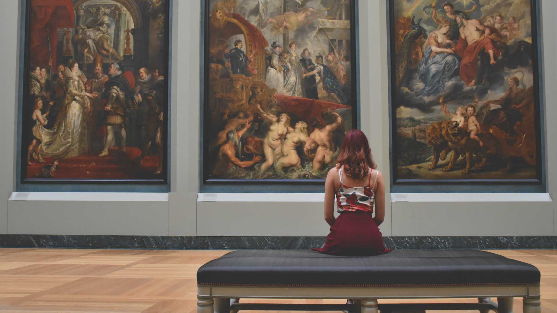 woman on a bench looking at art in a museum