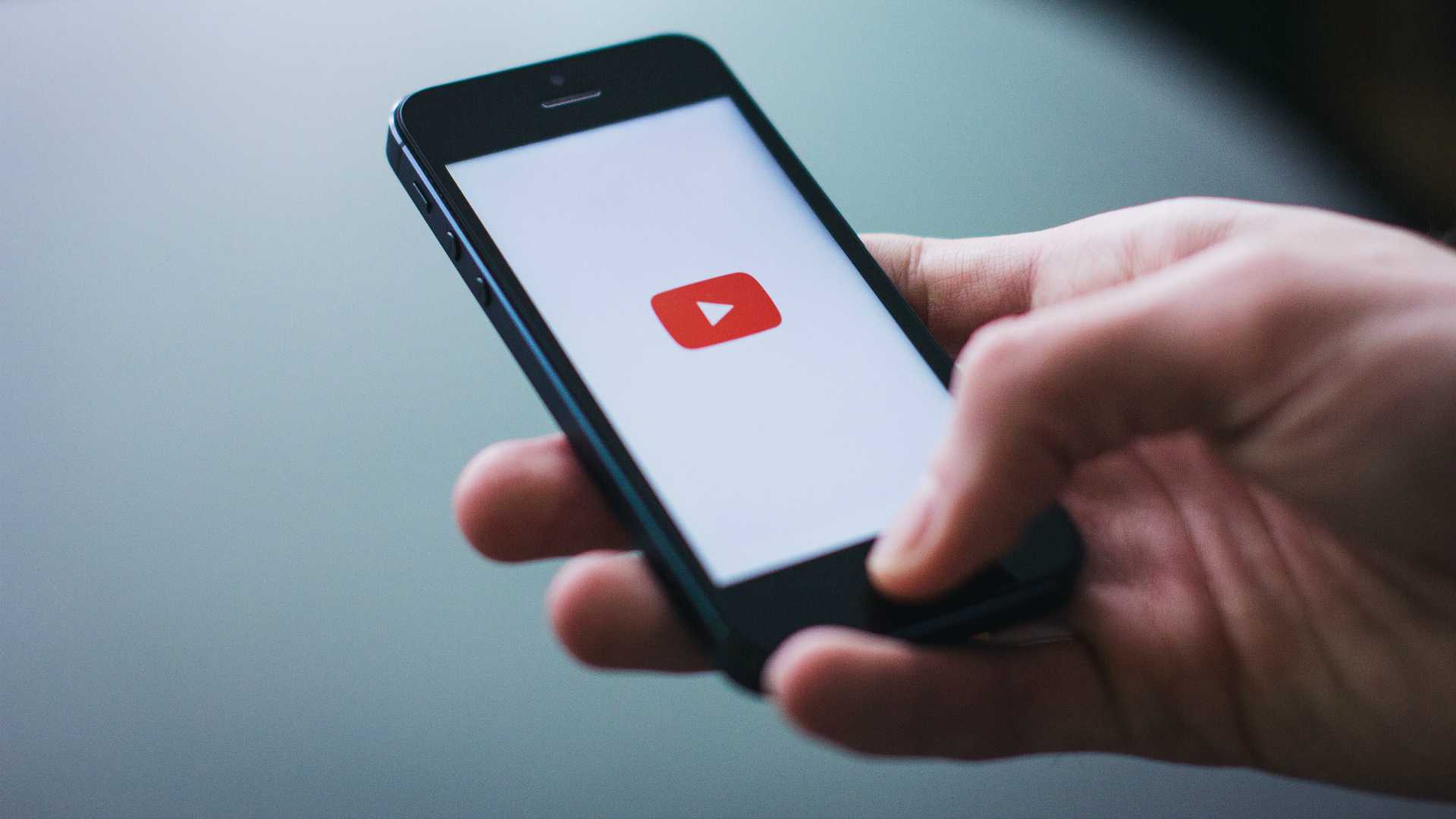 hand holding a phone with a "play video" icon