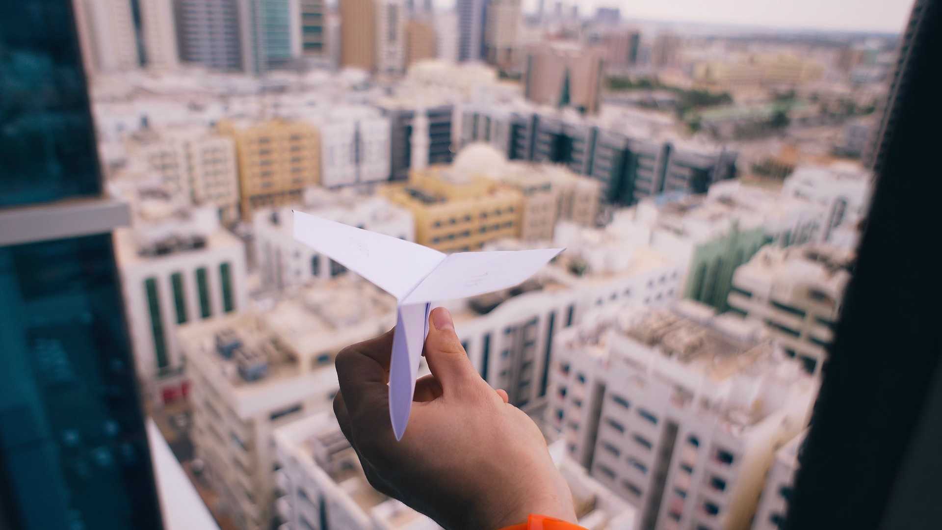 paper airplane at a window over skyscrapers