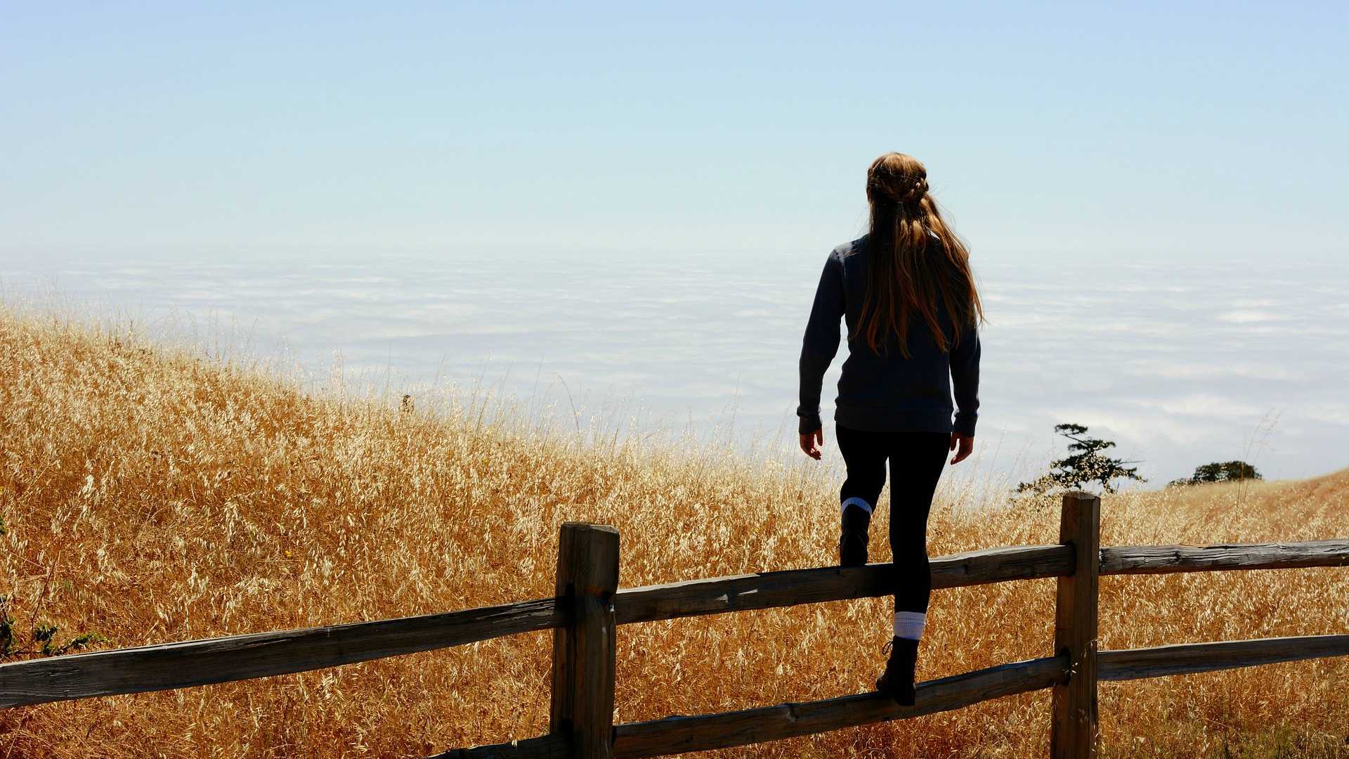 woman climbing over a fence