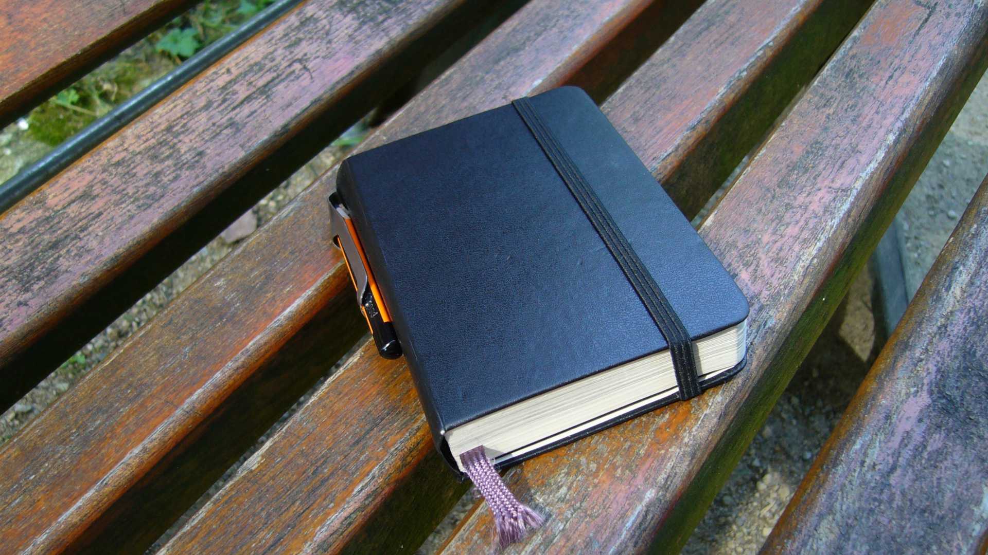 notebook with bookmark on a bench