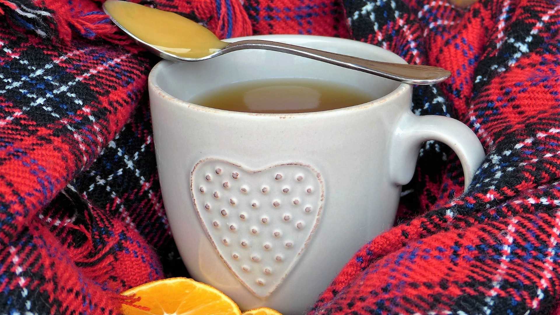 cup of tea with honey, oranges and a blanket