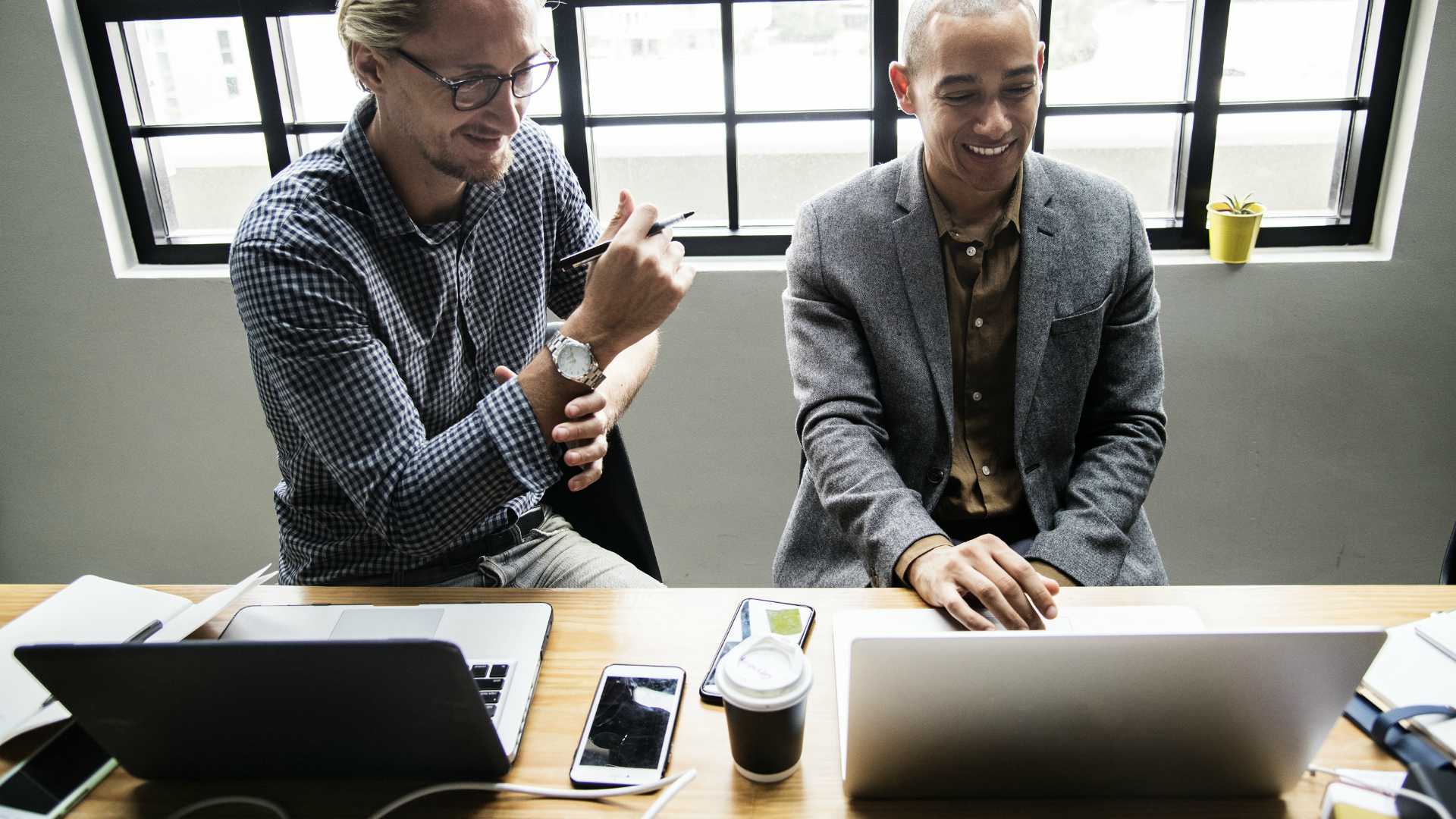 two men working together on laptops