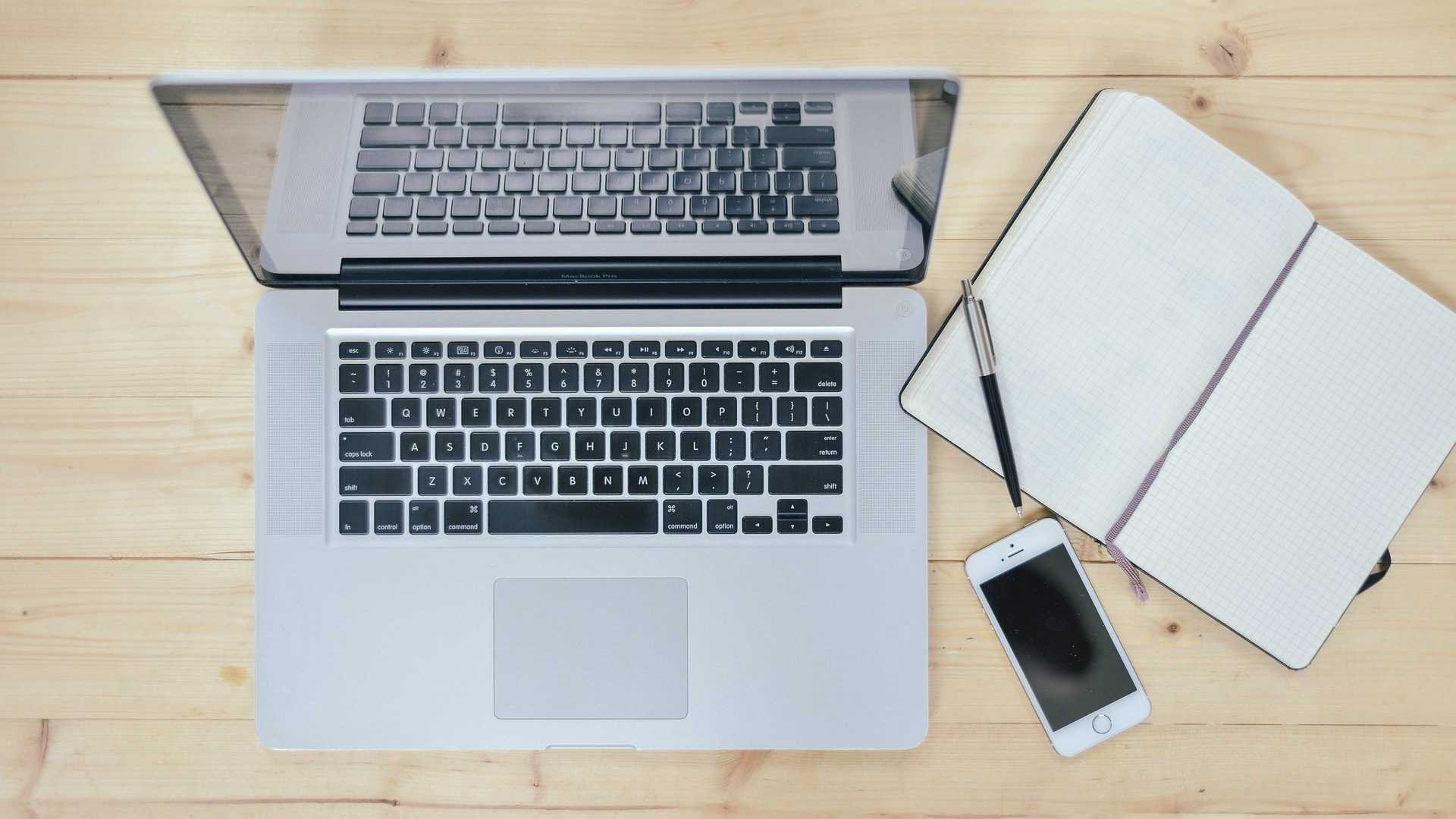 desk with laptop, phone, notebook and pen