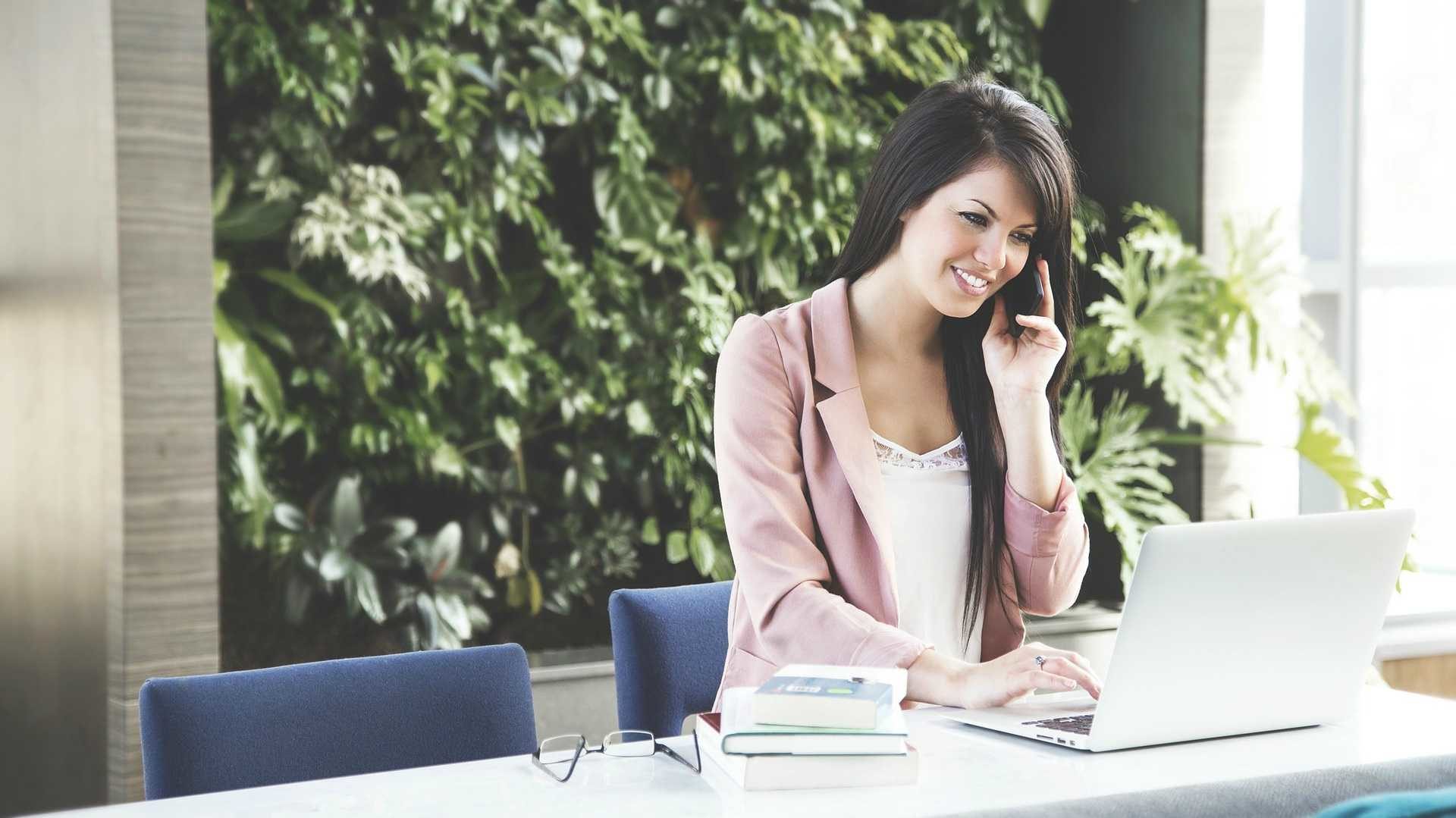 woman using a phone and a laptop