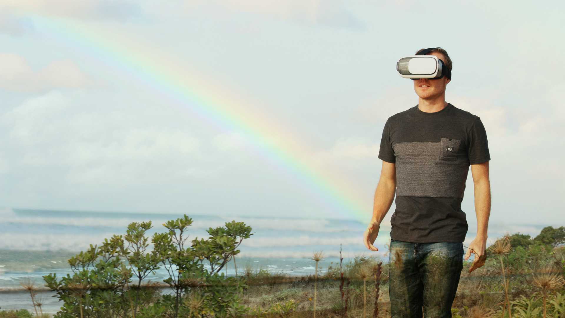 man using VR goggles, rainbow in the background
