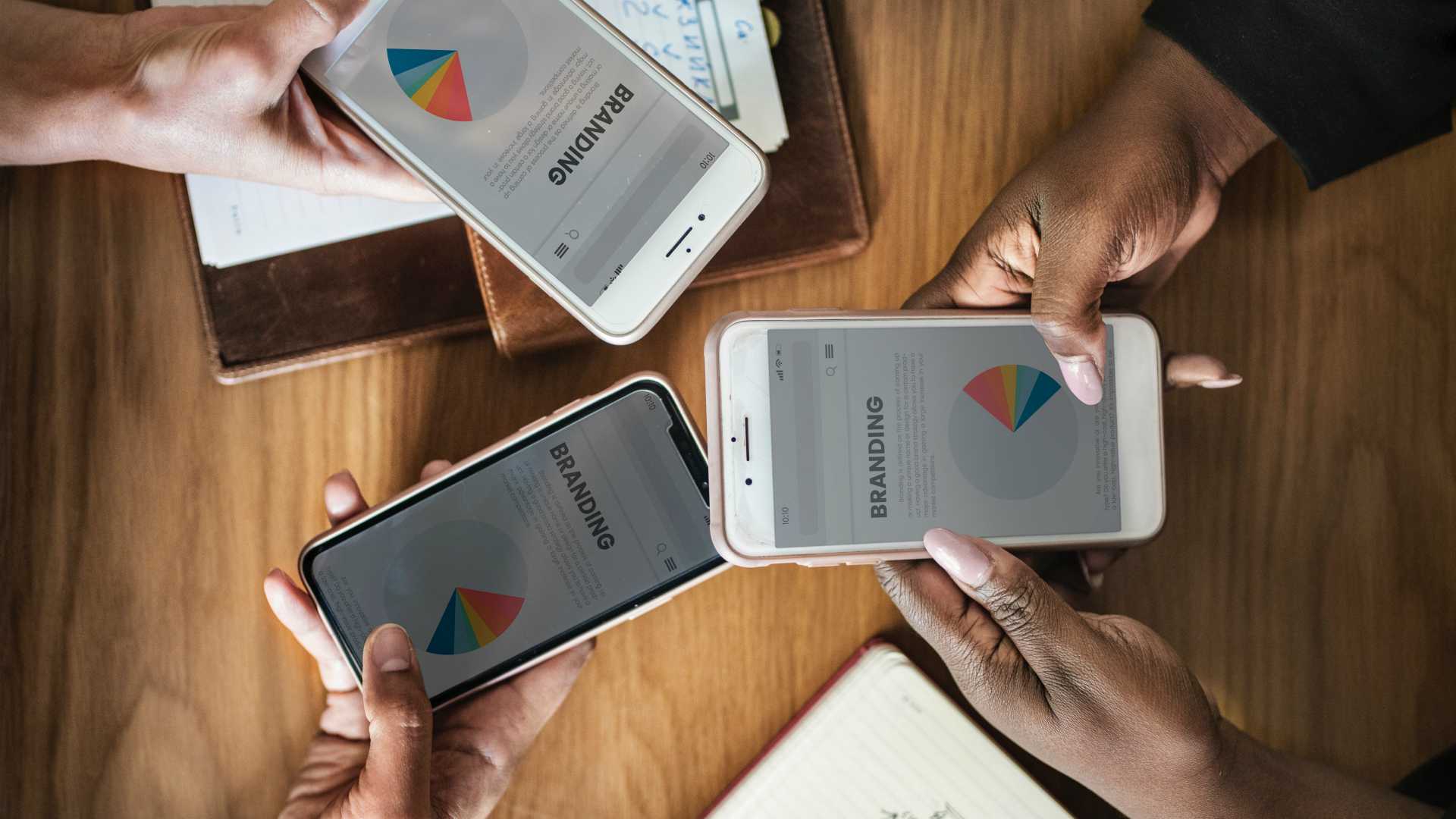 three people with mobile phones displaying branding charts