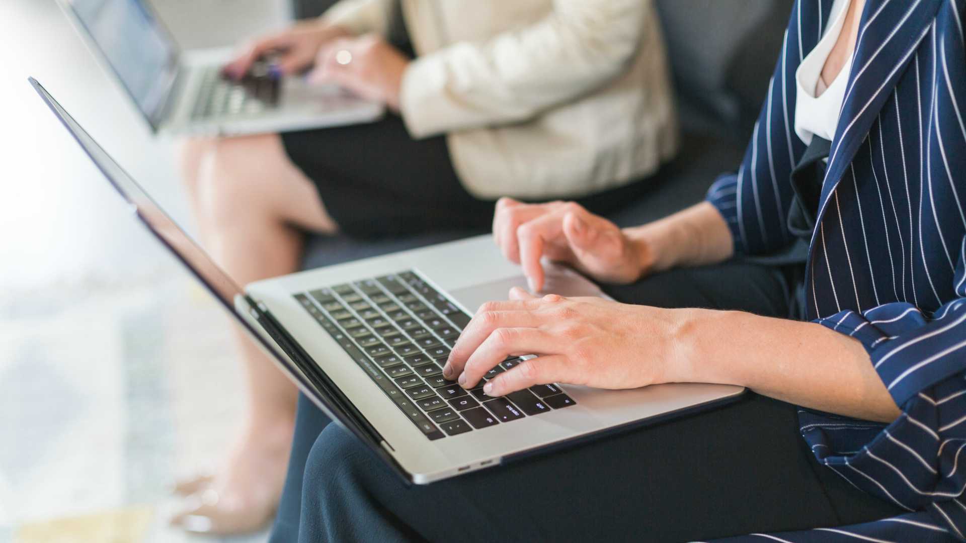 women working on laptops on a couch