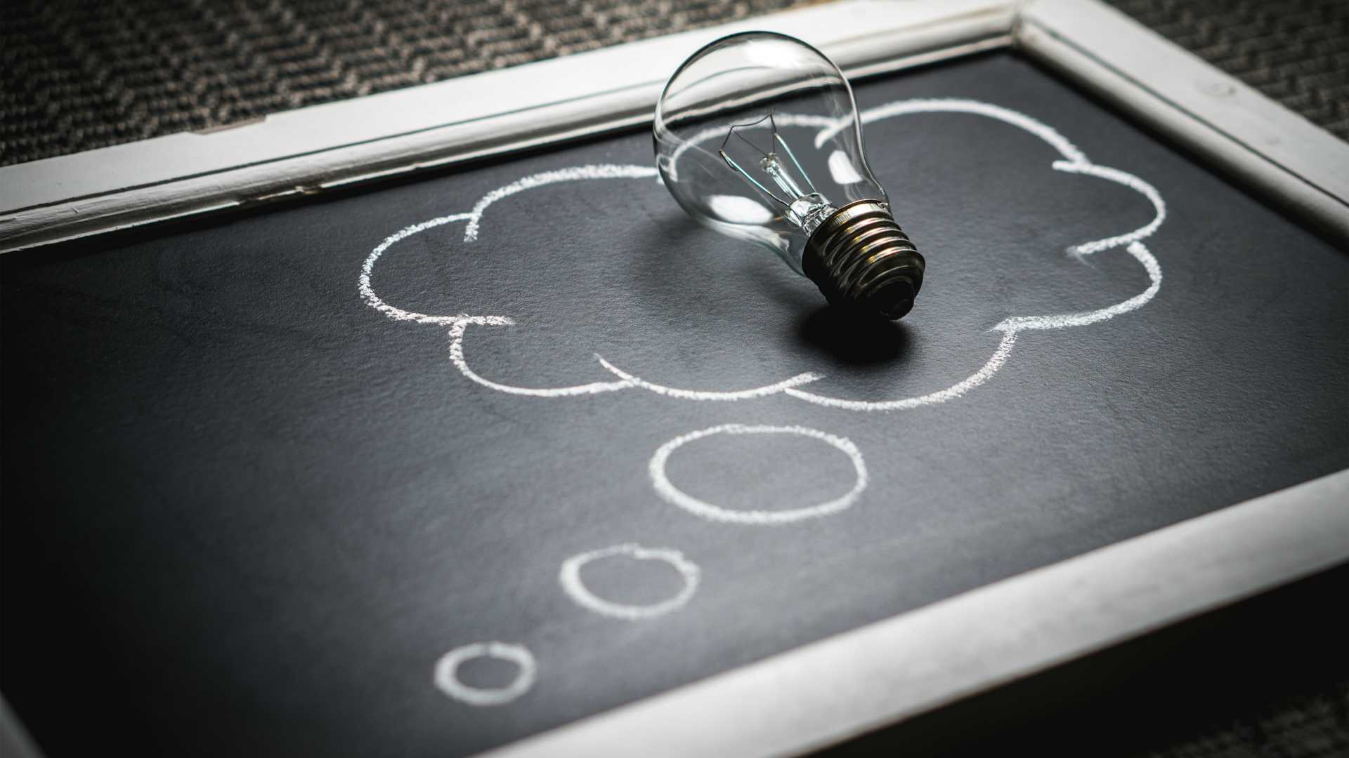 lightbulb on a chalkboard with a thought bubble drawn on it
