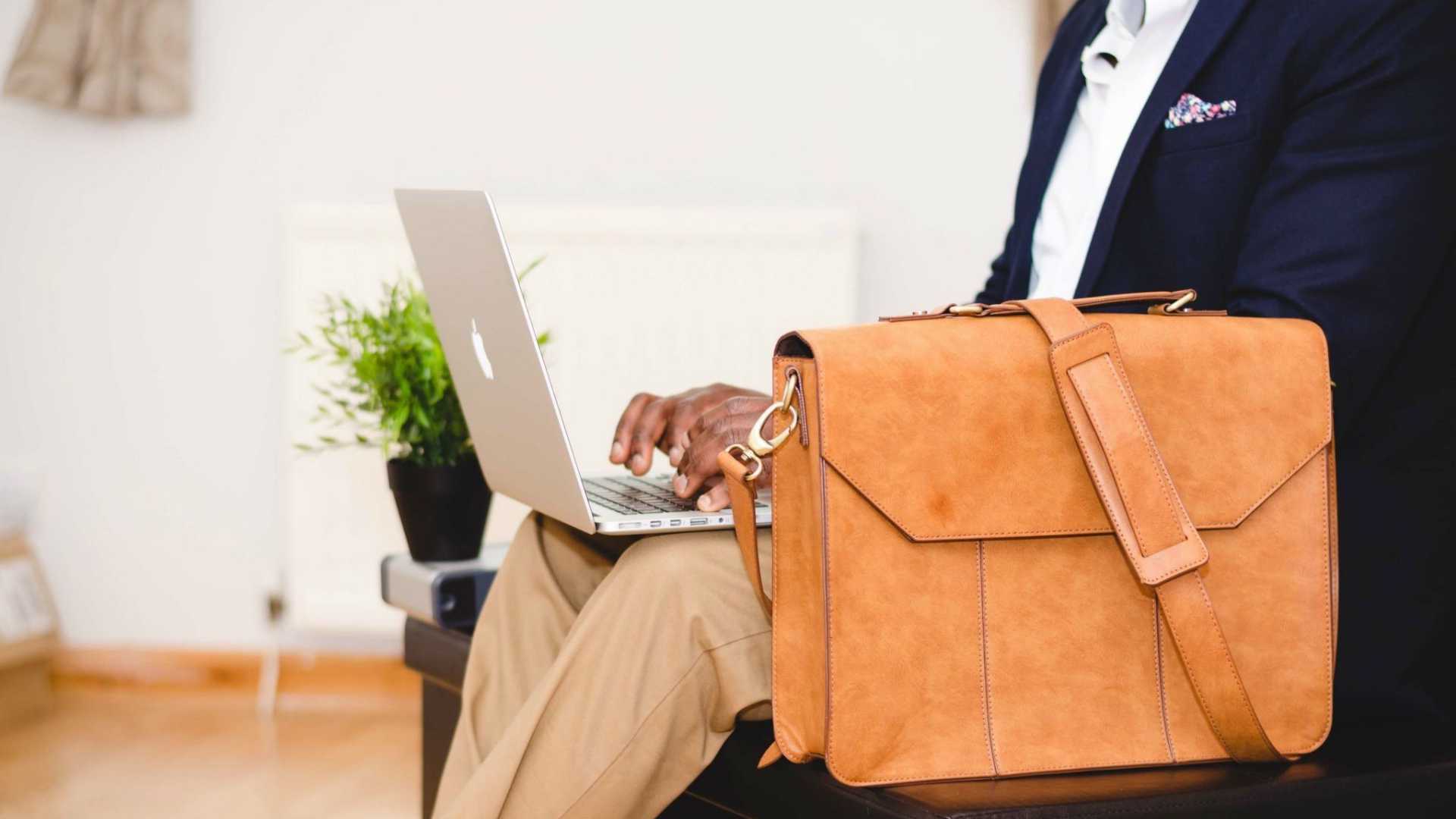 executive on a laptop next to a briefcase on a couch