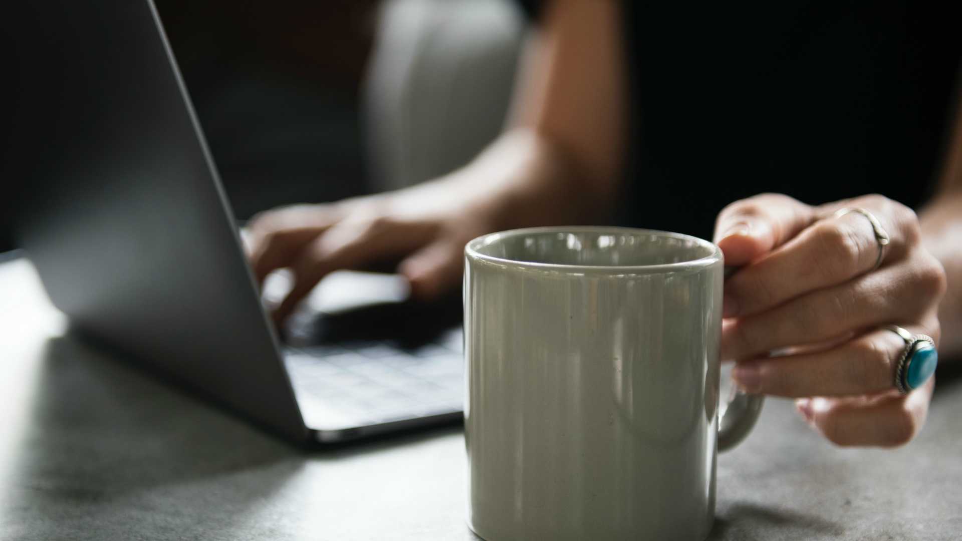 woman working on a laptop and drinking coffee