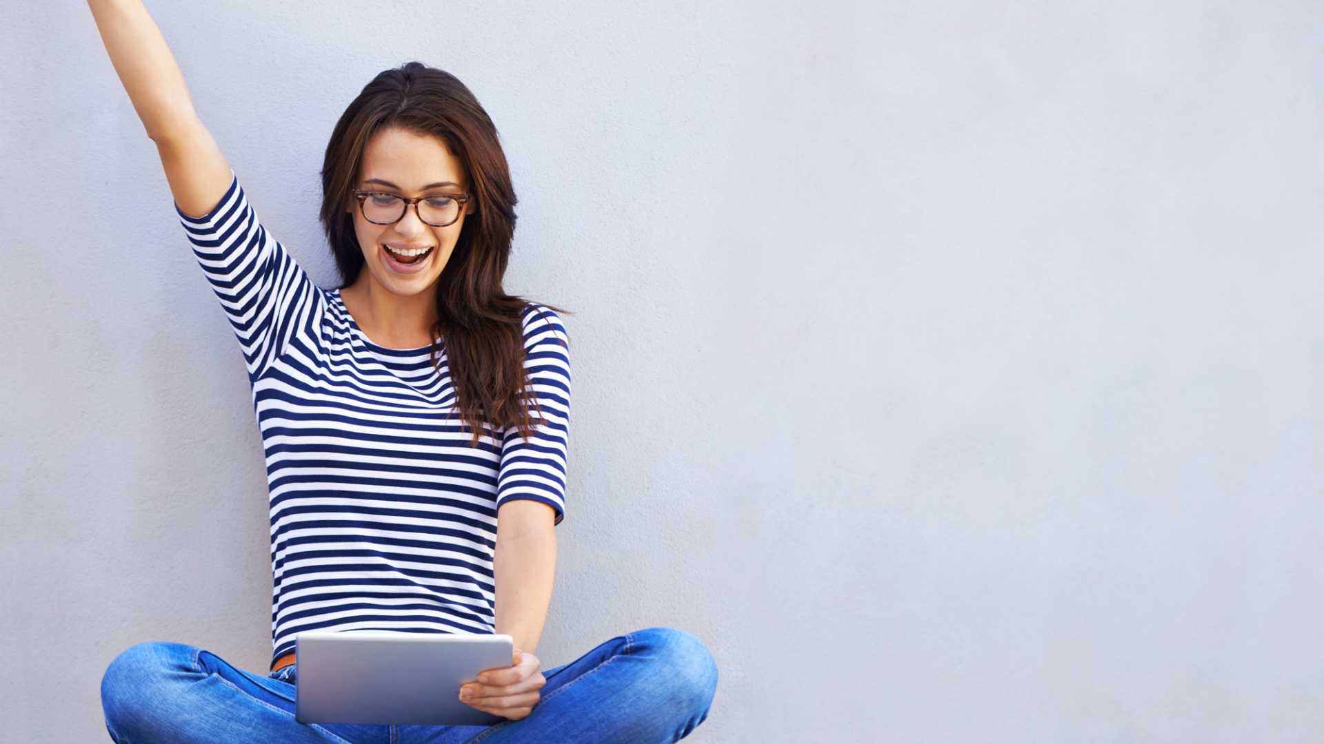 happy woman celebrating a win on a game on her tablet