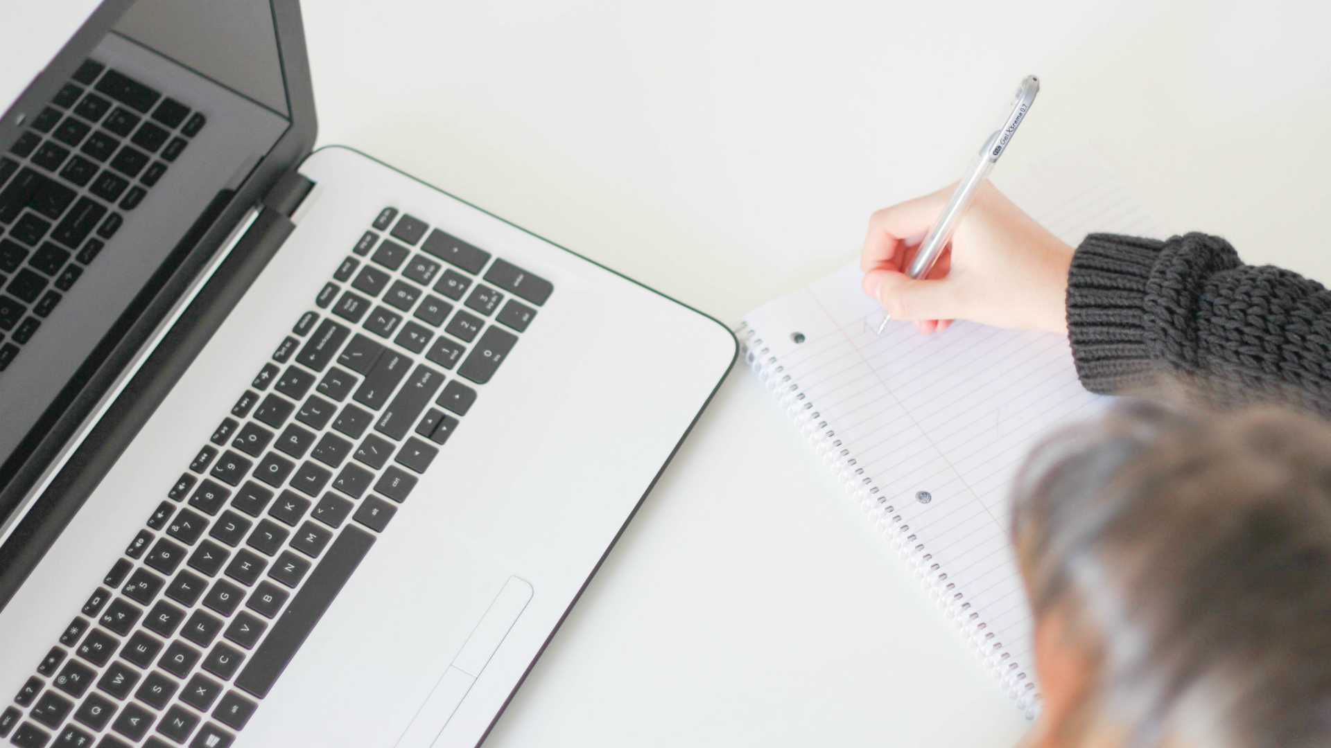 woman taking notes from a laptop screen