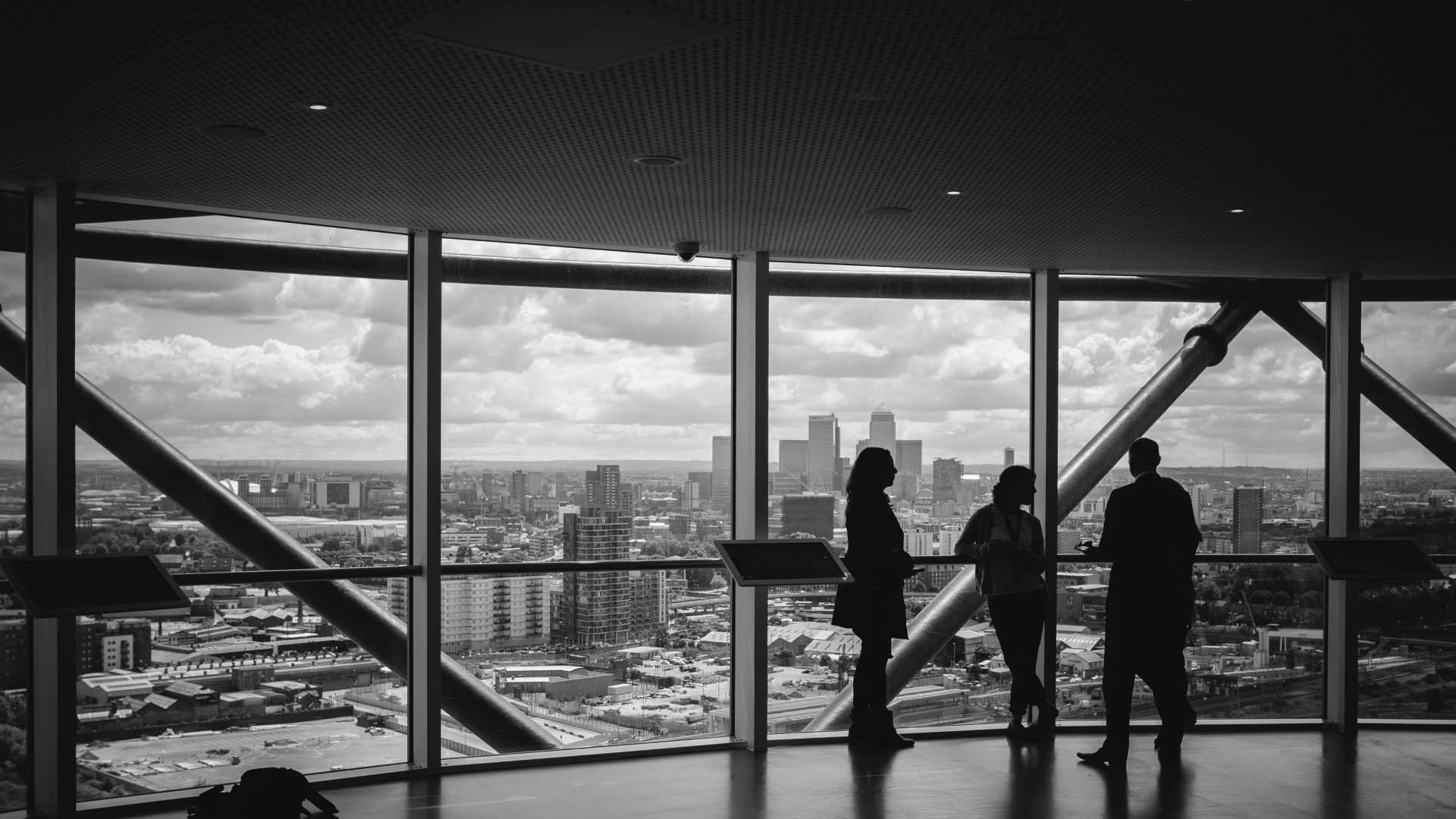 businesspeople standing in front of a large window in a skyscraper