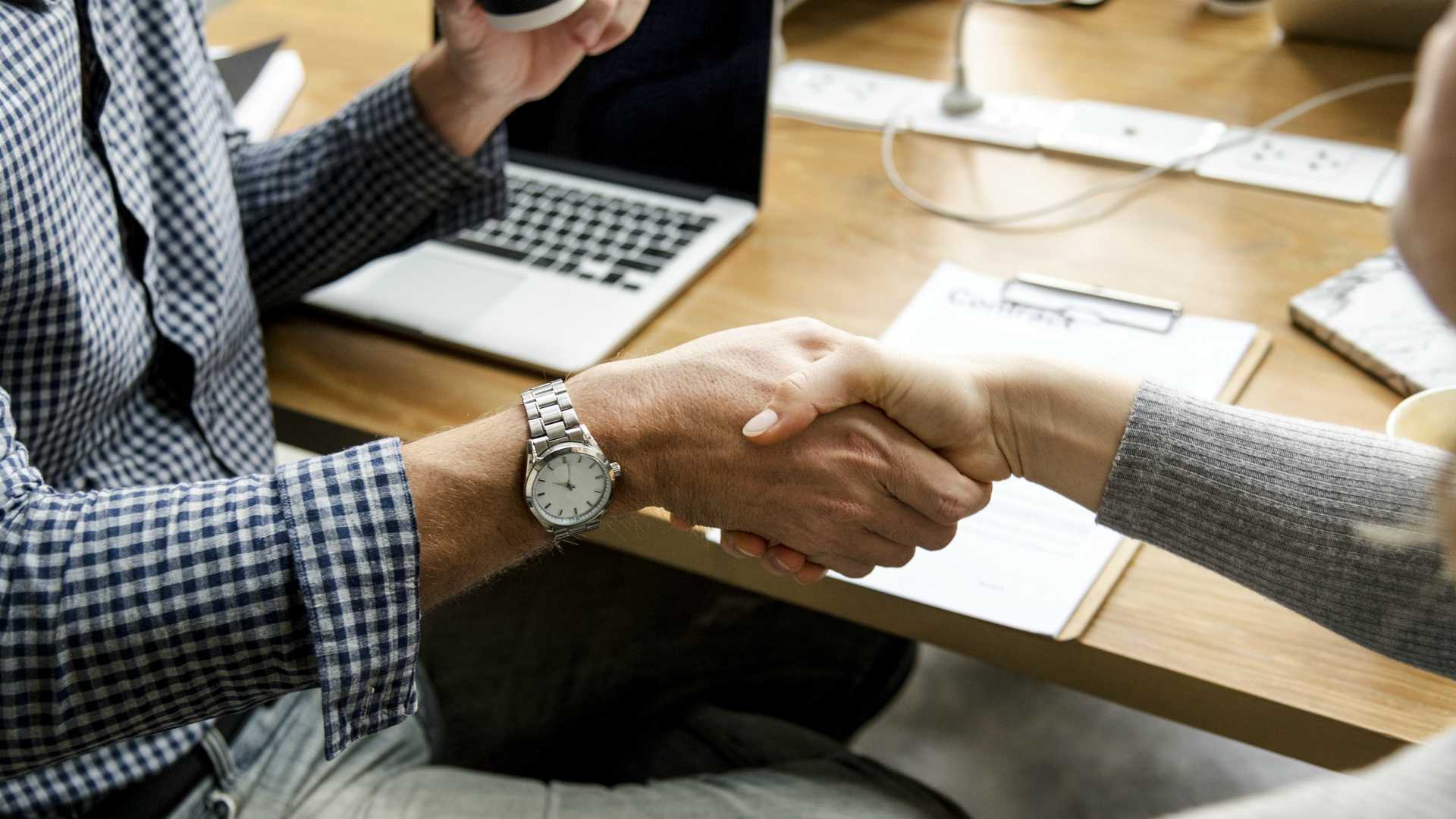 two professionals shaking hands over a contract