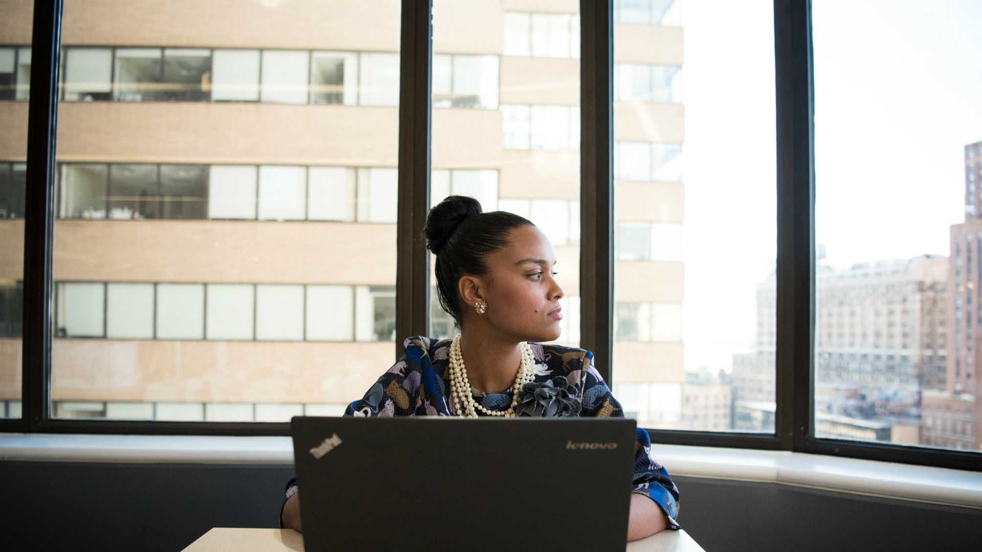 woman using a laptop and looking out the window