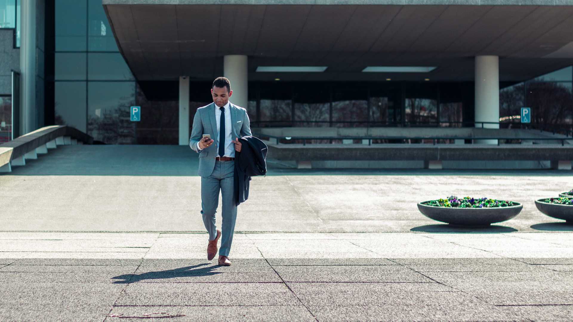 happy businessman leaving a building and looking at his smartphone