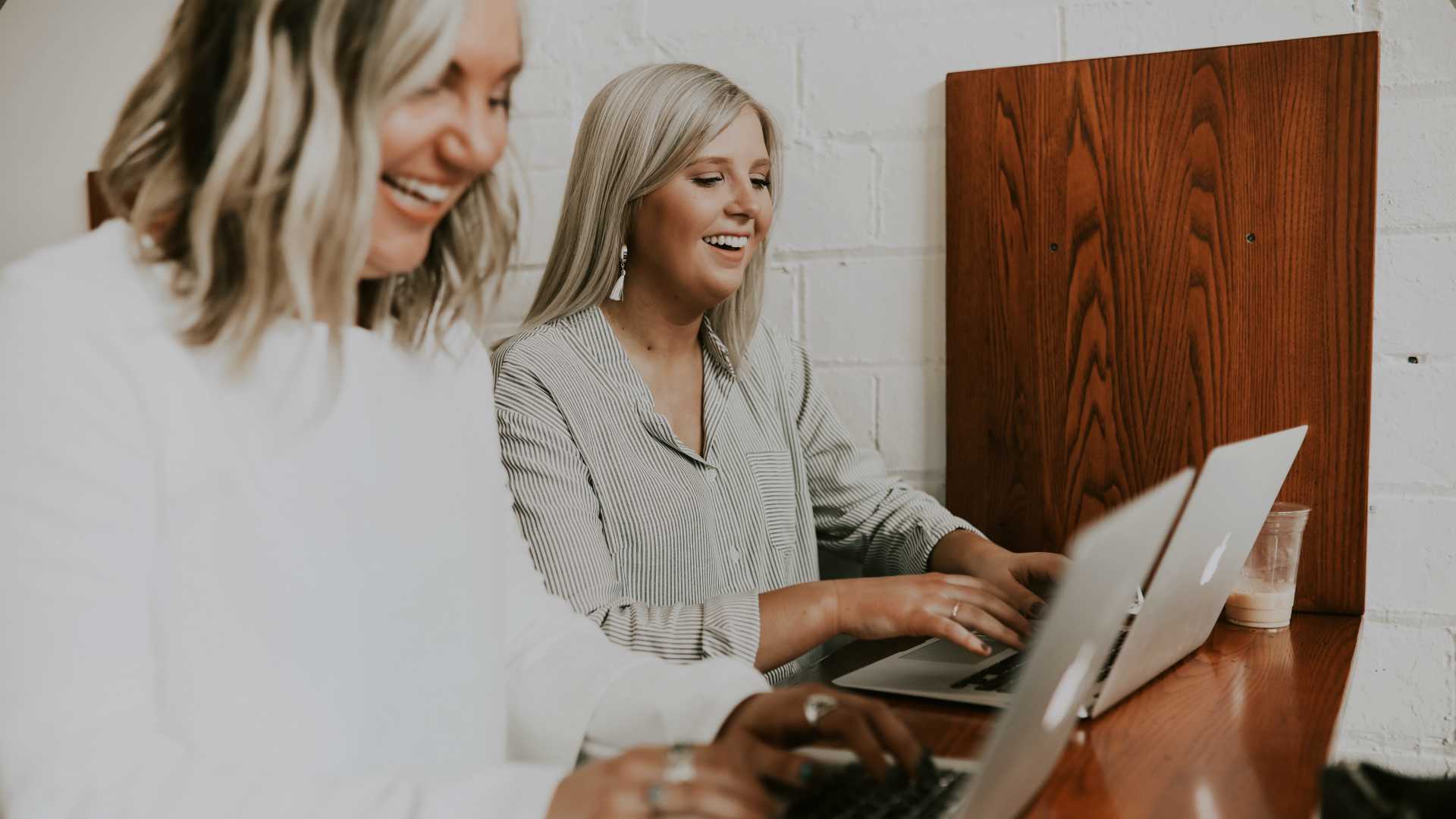 two women working on laptops happily