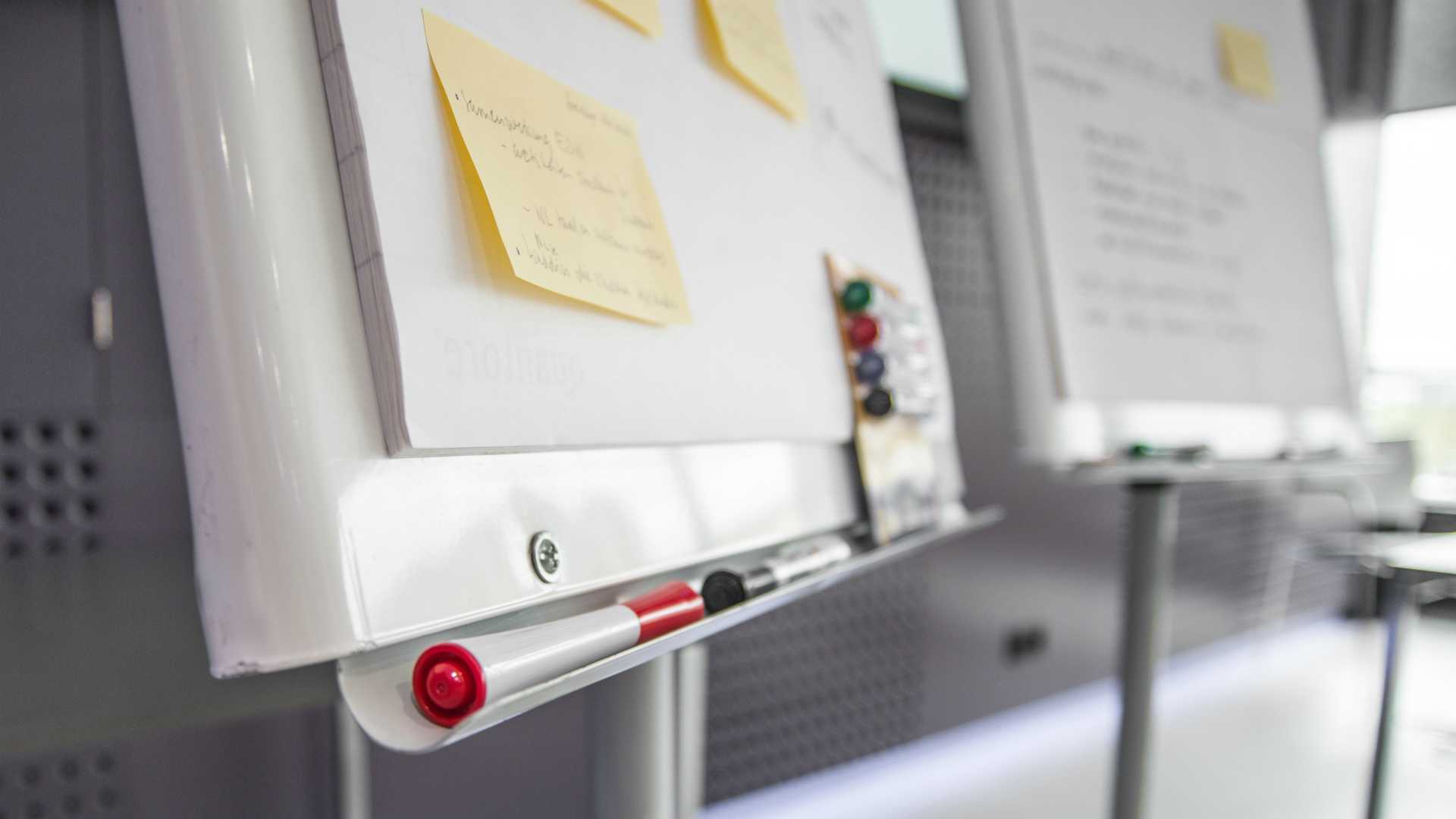 whiteboard with sticky notes and markers on it
