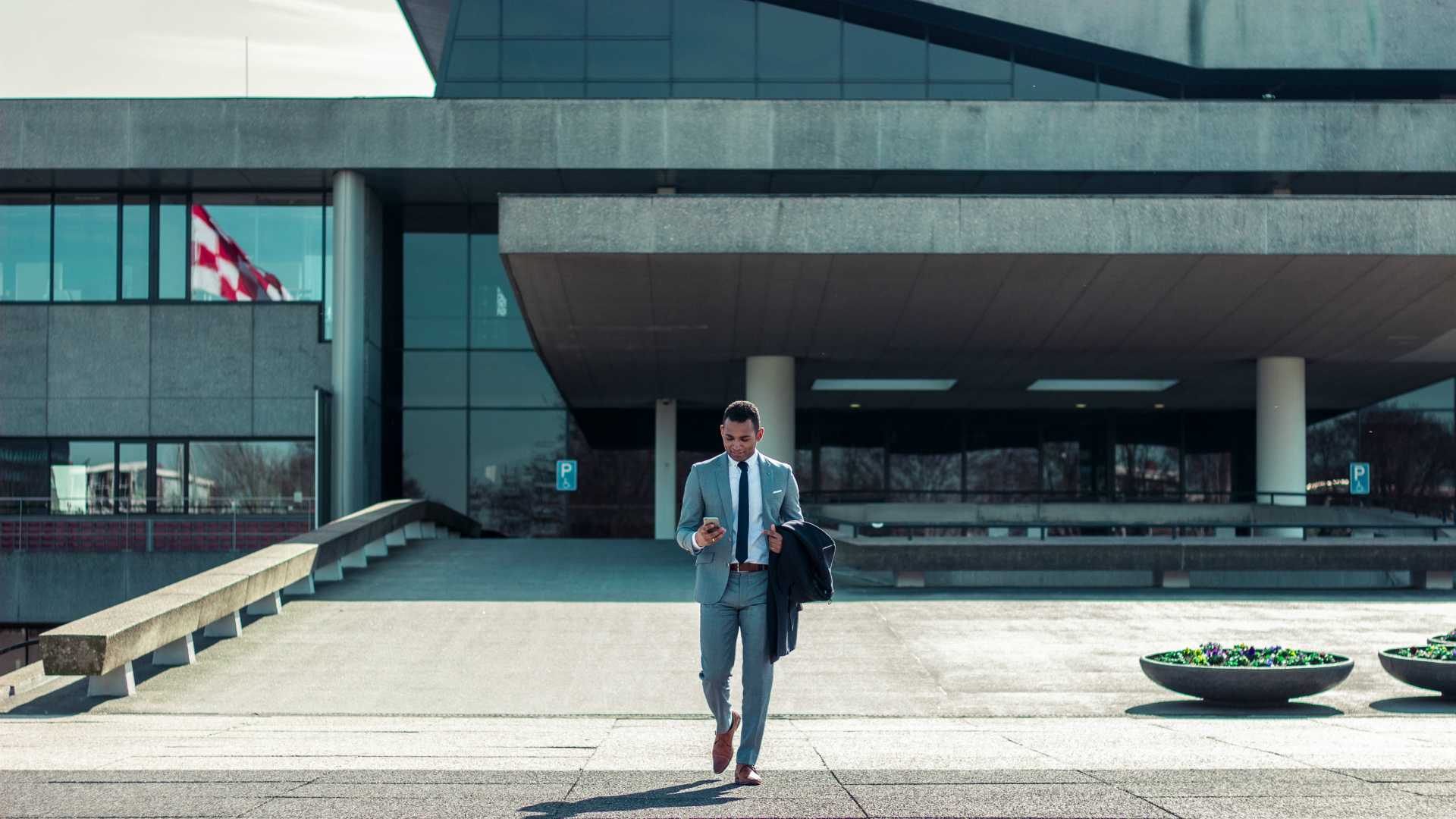 businessman leaving a building and looking at his phone