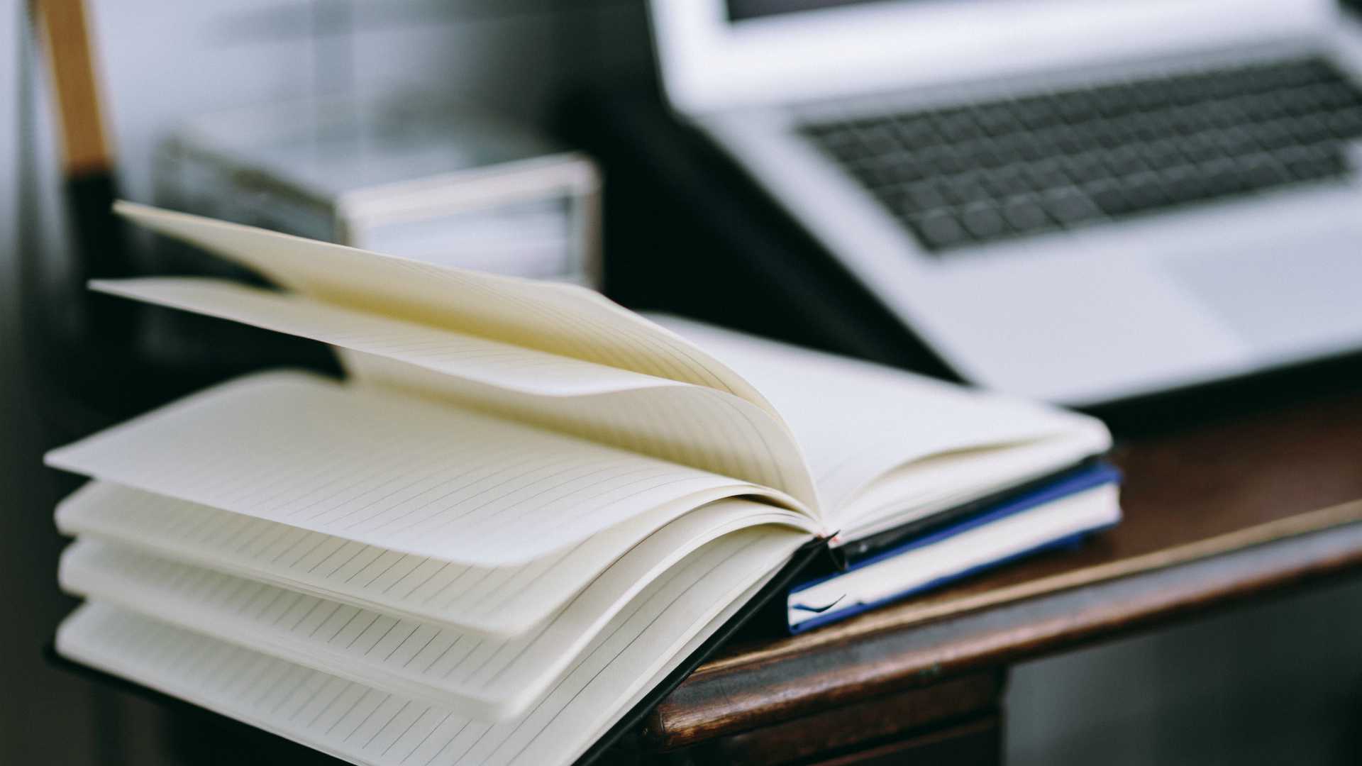 desk with laptop, business cards, and an open notebook