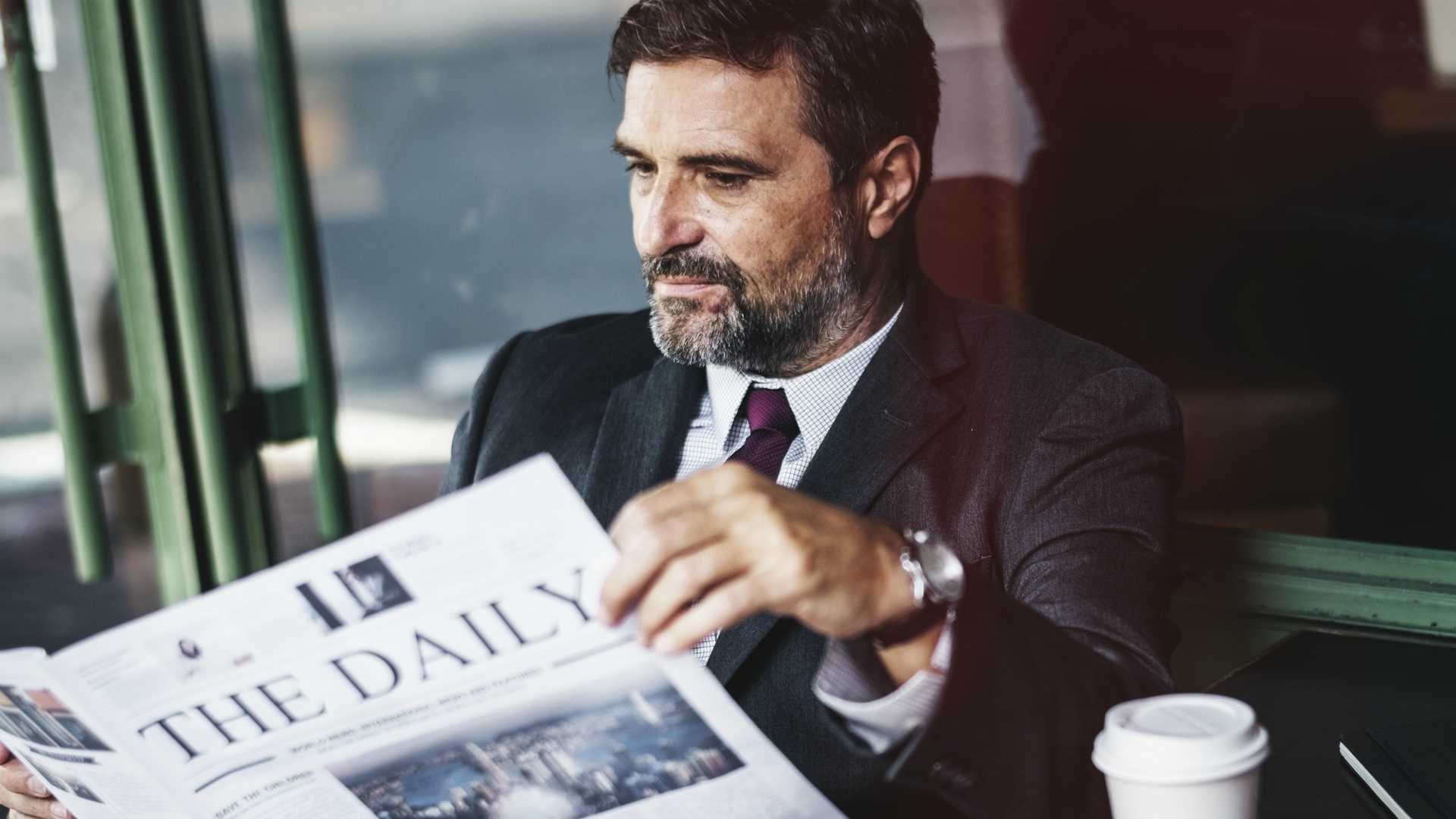 businessman reading a newspaper and drinking coffee
