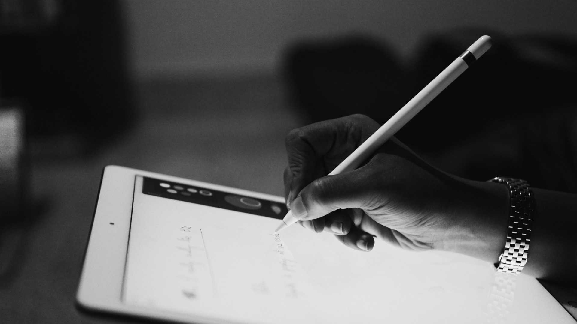 black and white photo of a woman's hand writing on a tablet with a stylus