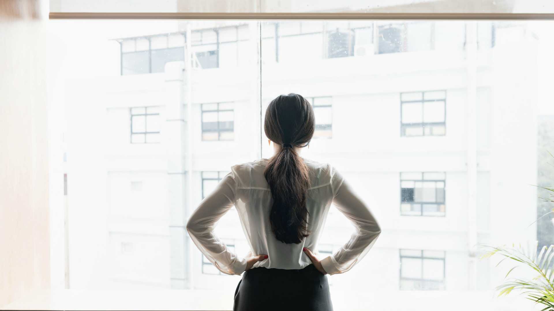 businesswoman looking out the window of her executive office
