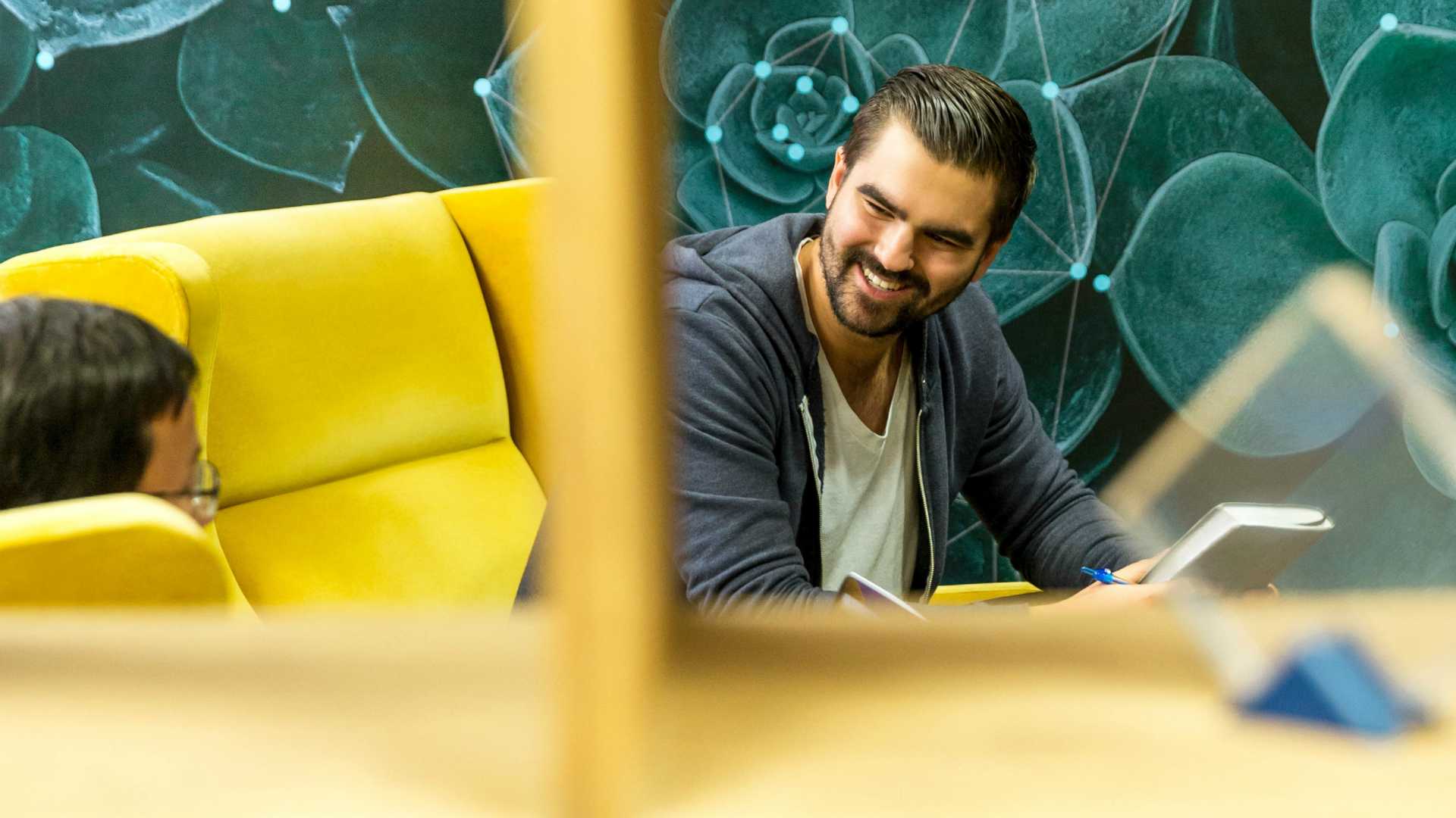 view from outside a window of two businessmen smiling and talking with each other on a couch