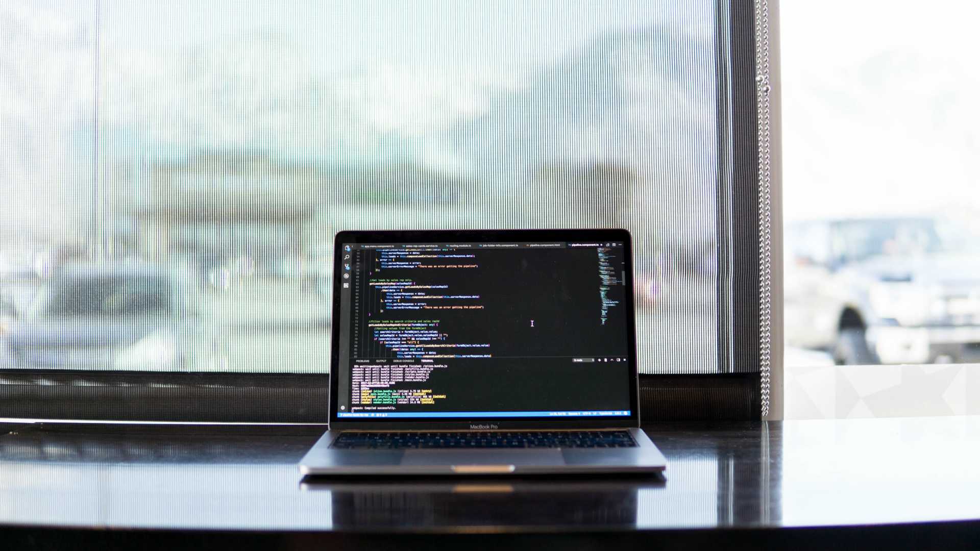laptop with code on it sitting on a table in front of a window