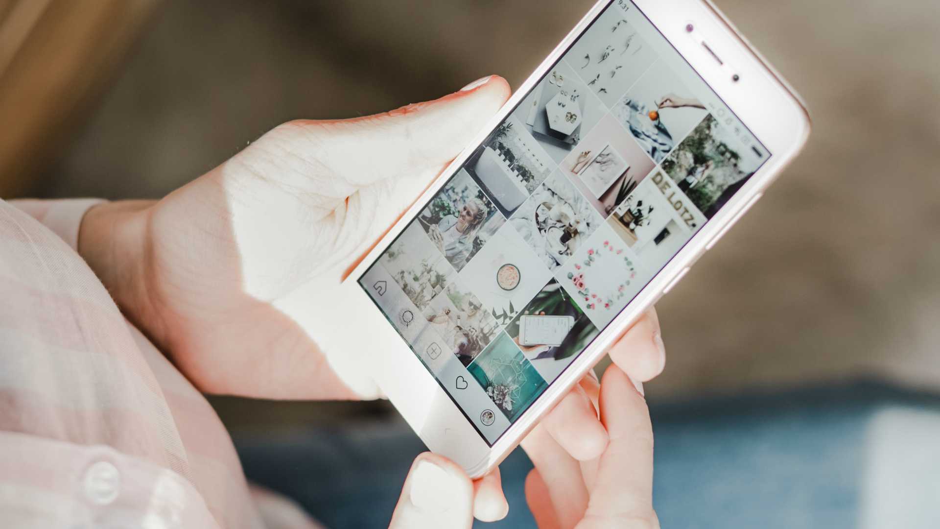 woman's hands looking at a social media collection of images on her smartphone