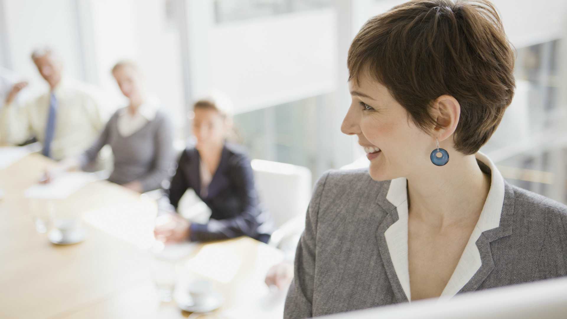 businesswoman making a presentation with her head turned to the people sitting at the conference table