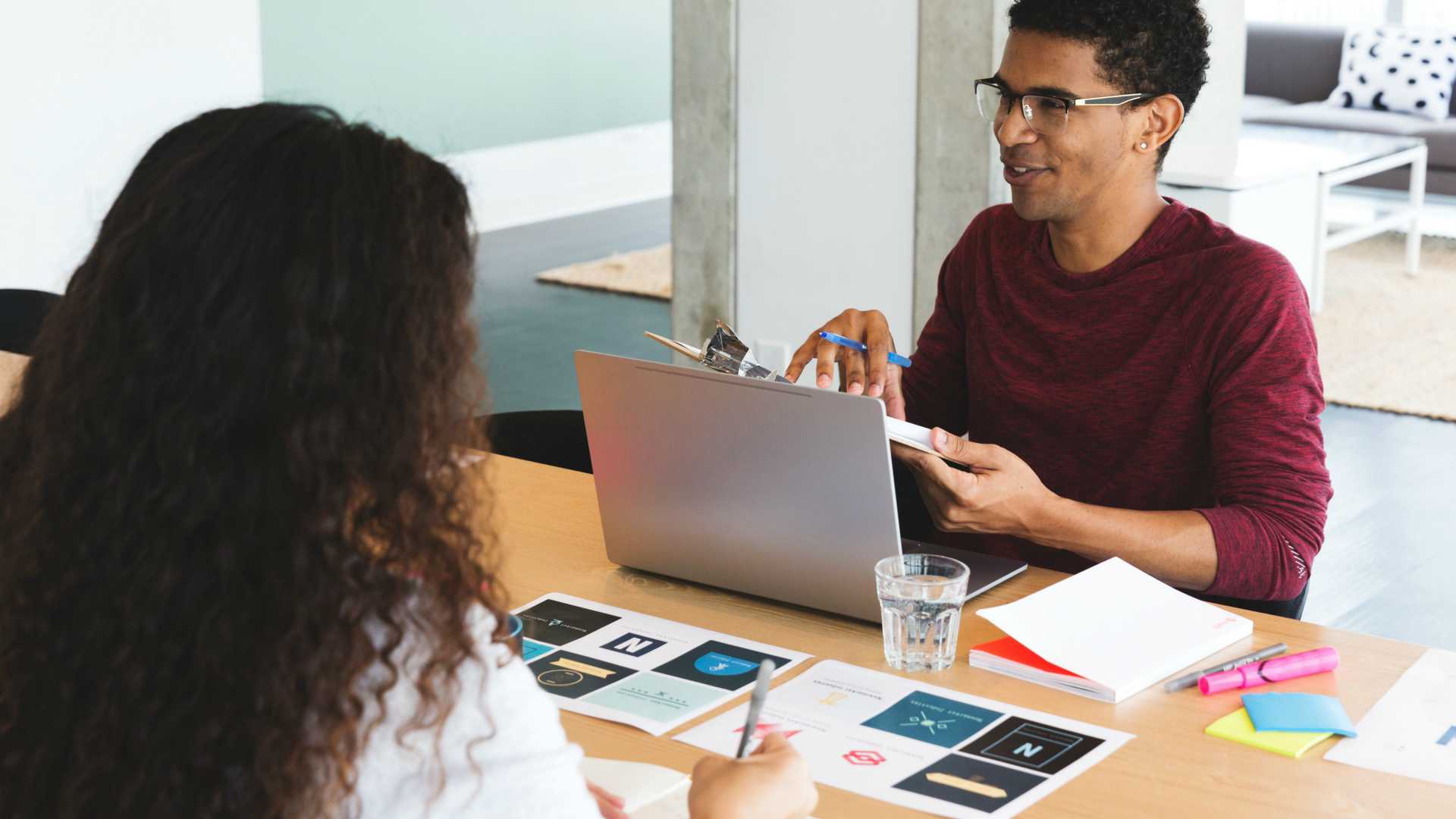 two people in a design meeting, one of whom is talking and facing a laptop