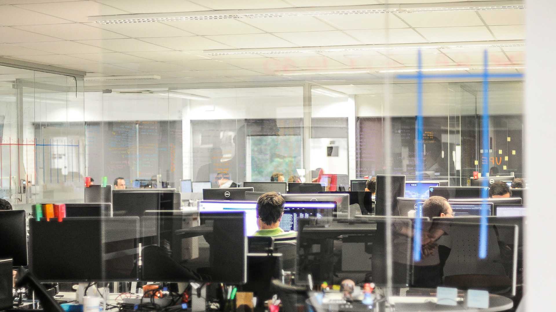 open tech office with a few employees working on coding projects
