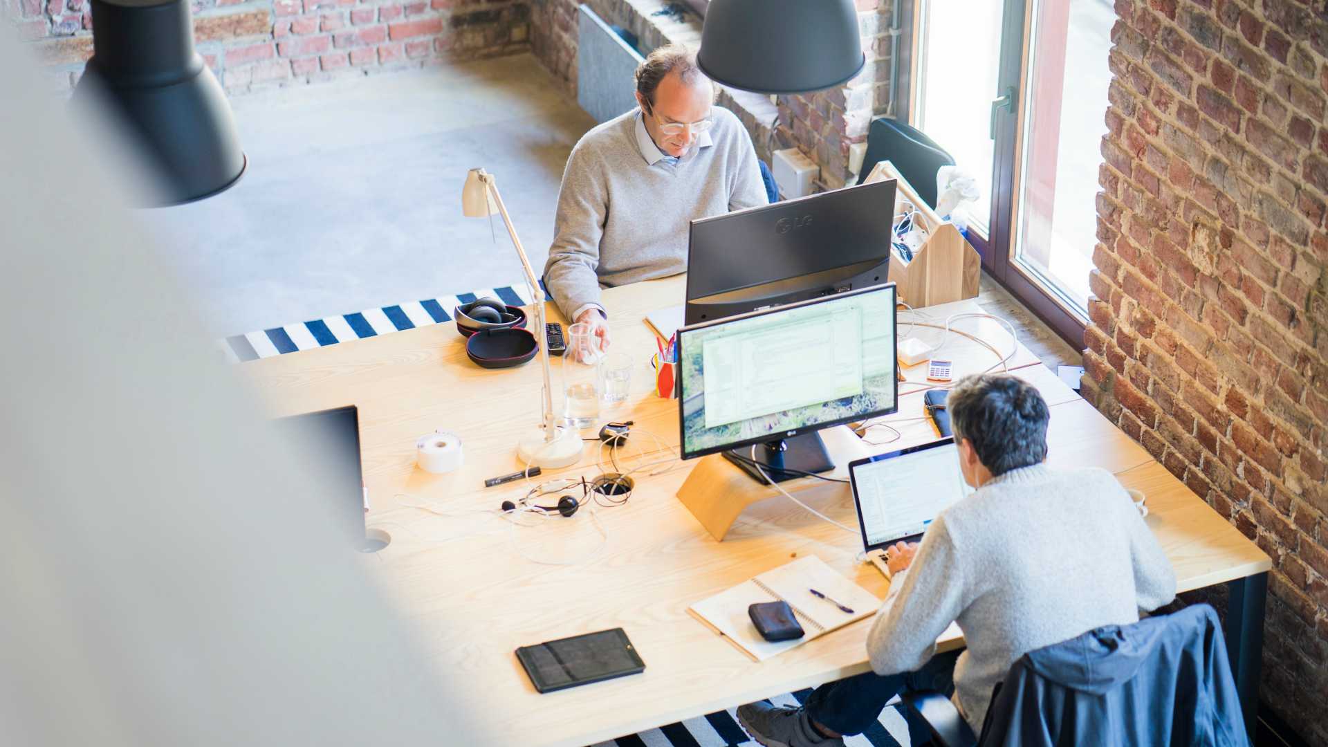 two men working on computers in an open office