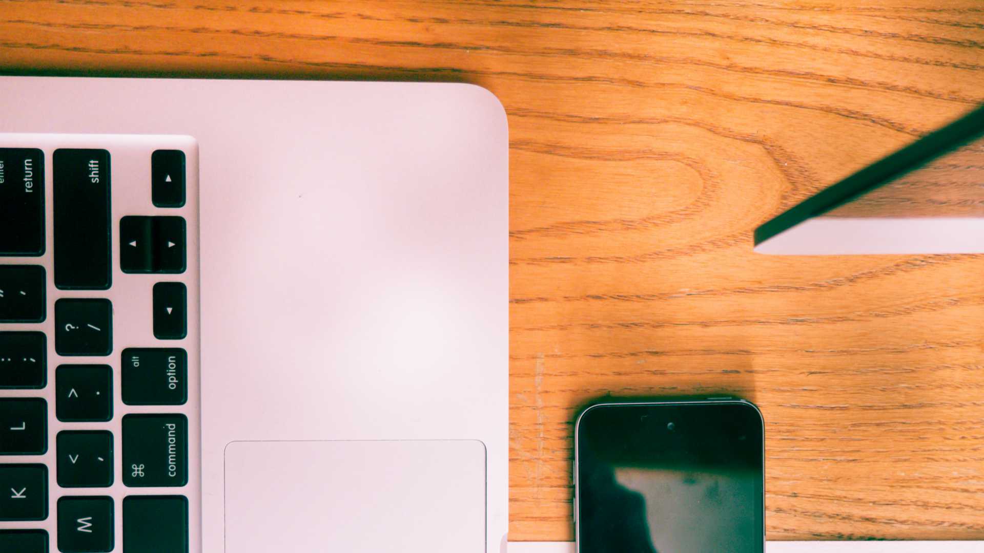 desk with a pinkish laptop and smartphone