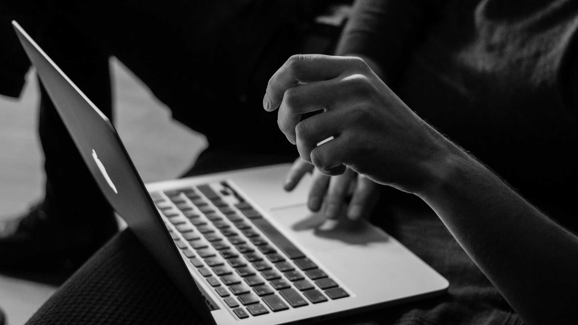 woman's hands using a Macbook on her lap