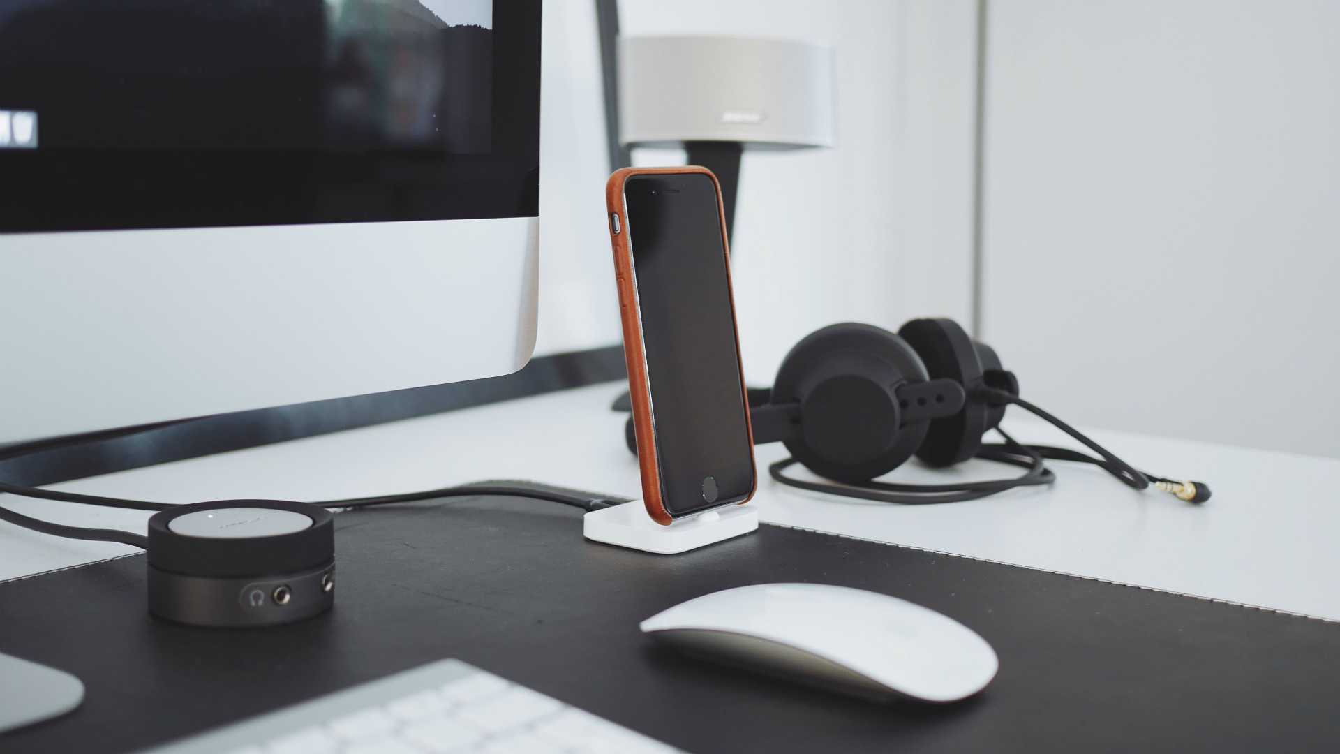 desk with computer, headphones, smartphone and speaker