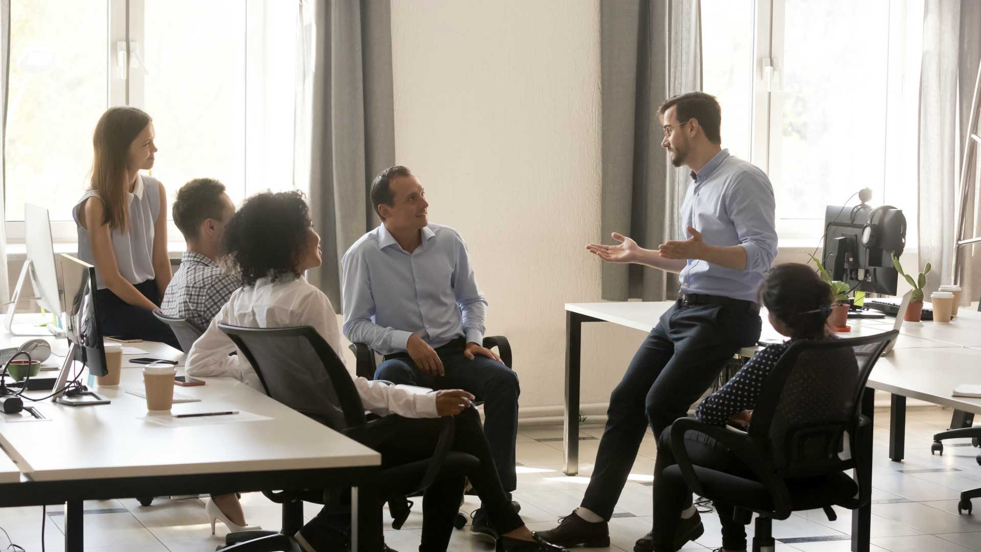 Male team leader boss talking to diverse business people at a casual office meeting