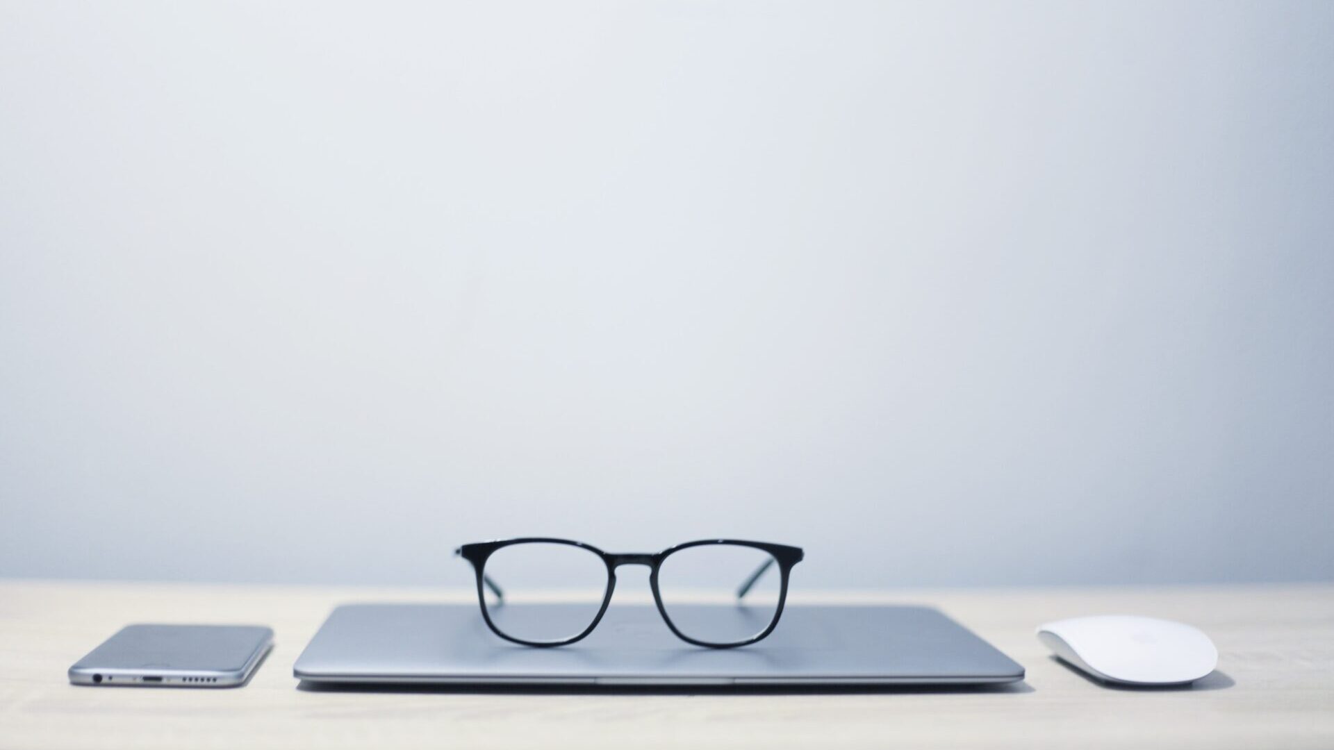 Black-frame glass sitting on top of laptop on tidy desk