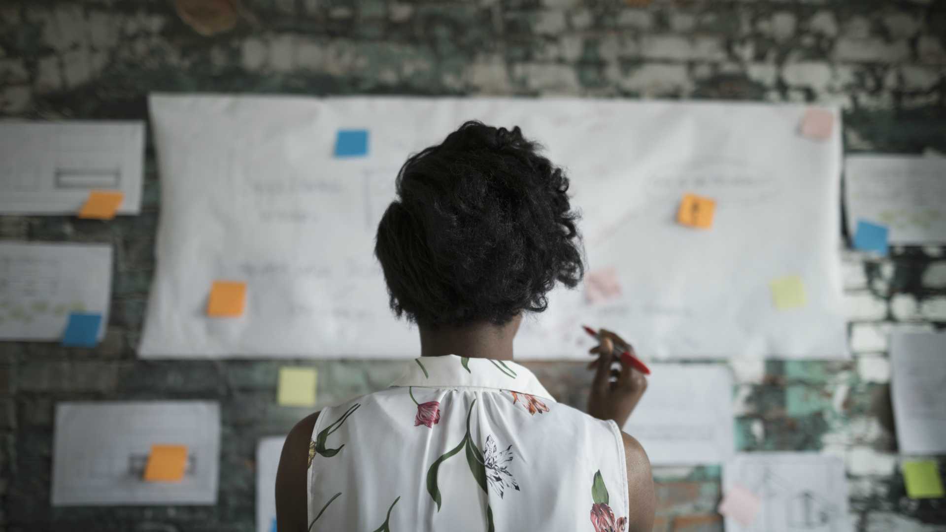 view from behind of an African-American woman working on a mapping exercise on a wall