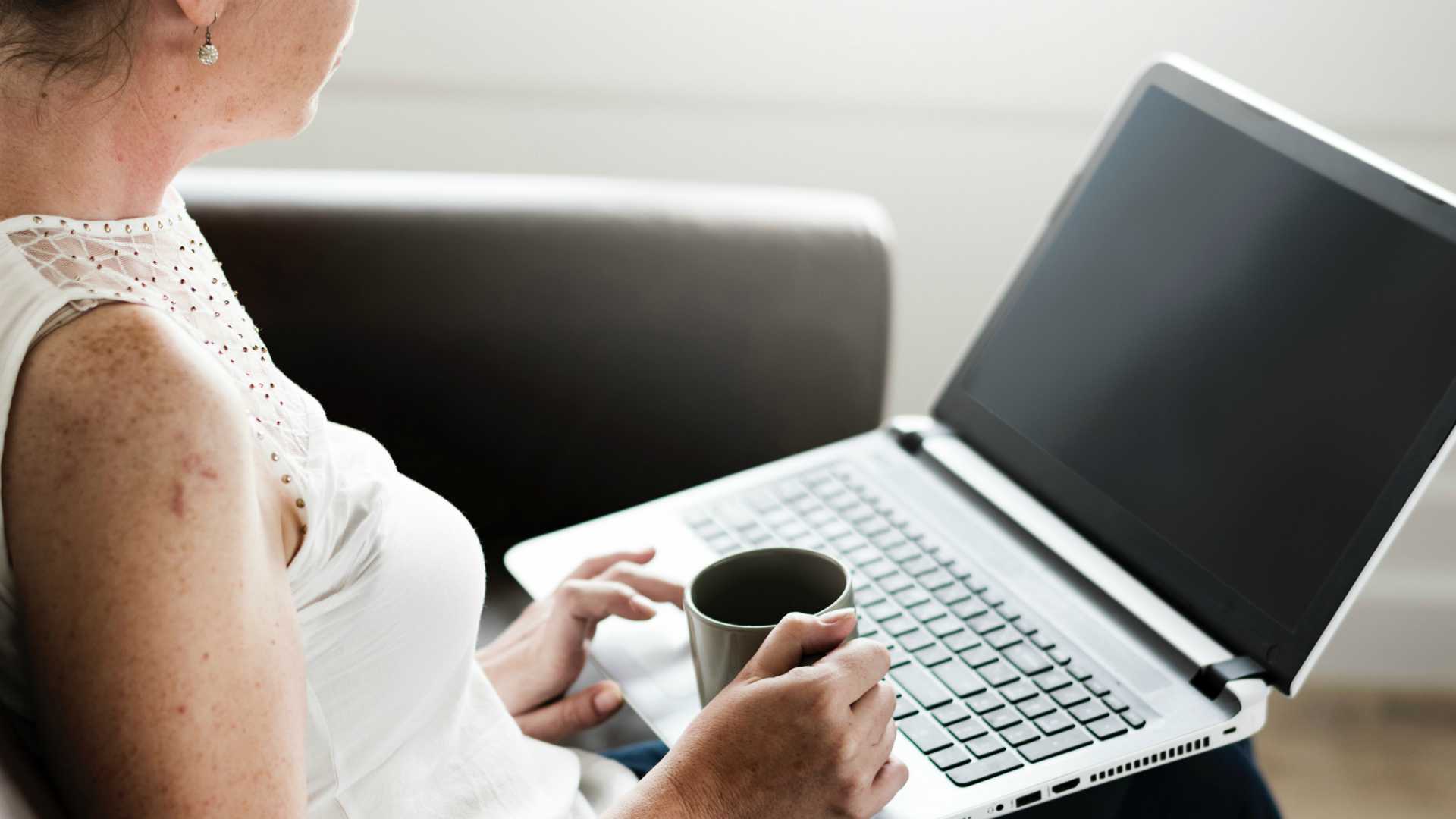 Busienss woman in white shirt with coffee working on laptop