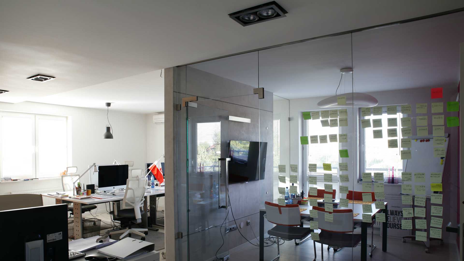Modern workplace with glass conference room covered in post-it note ideas